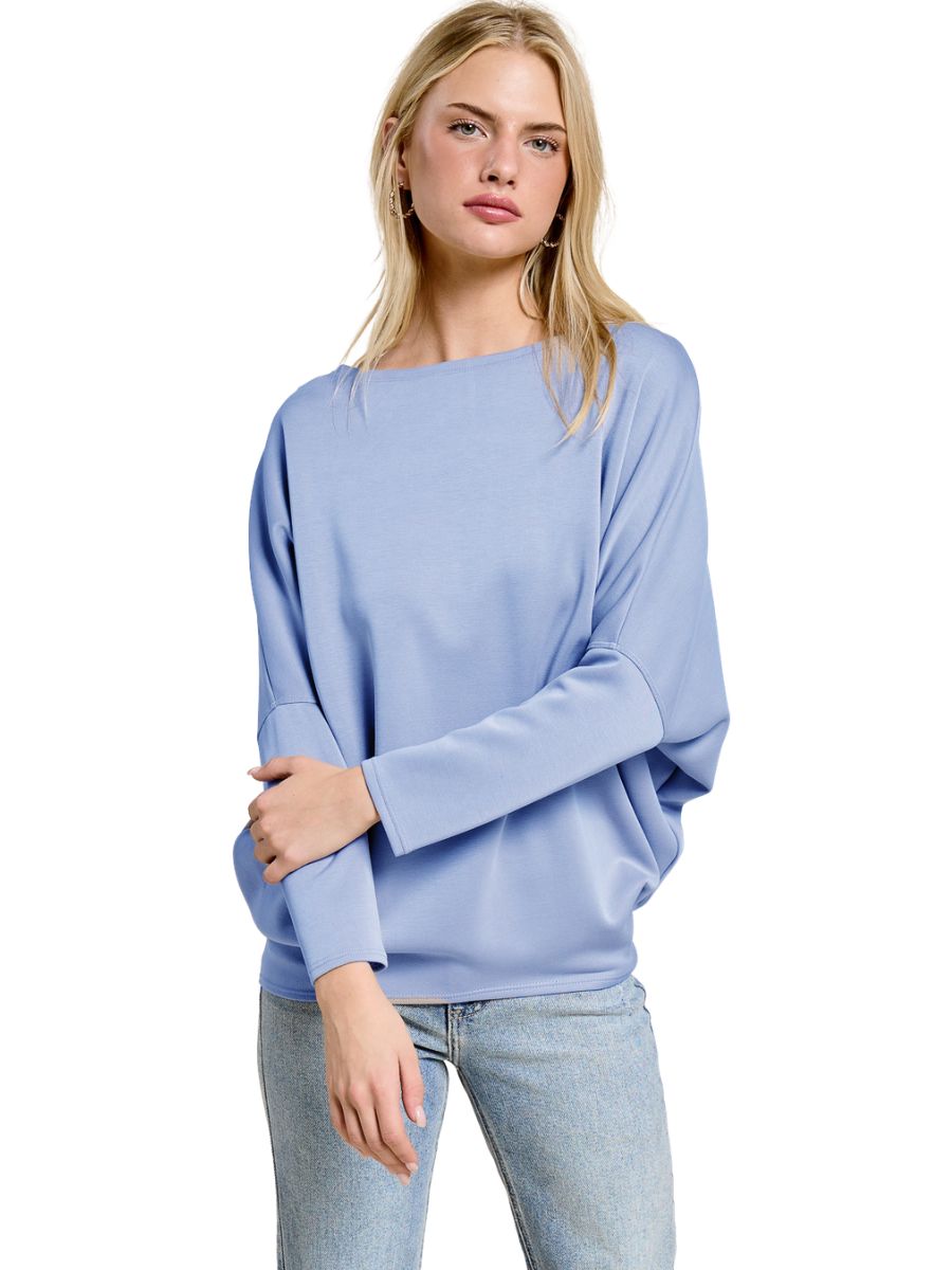 Light blue long-sleeve loose fit top paired with light wash denim jeans on a neutral background.