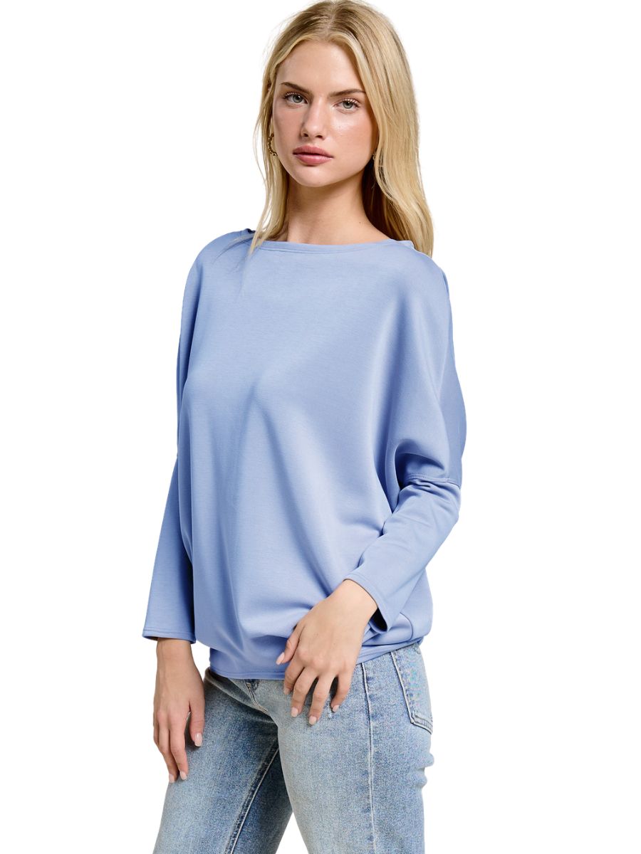Light blue long-sleeve top paired with light wash denim jeans on a model against a white background.