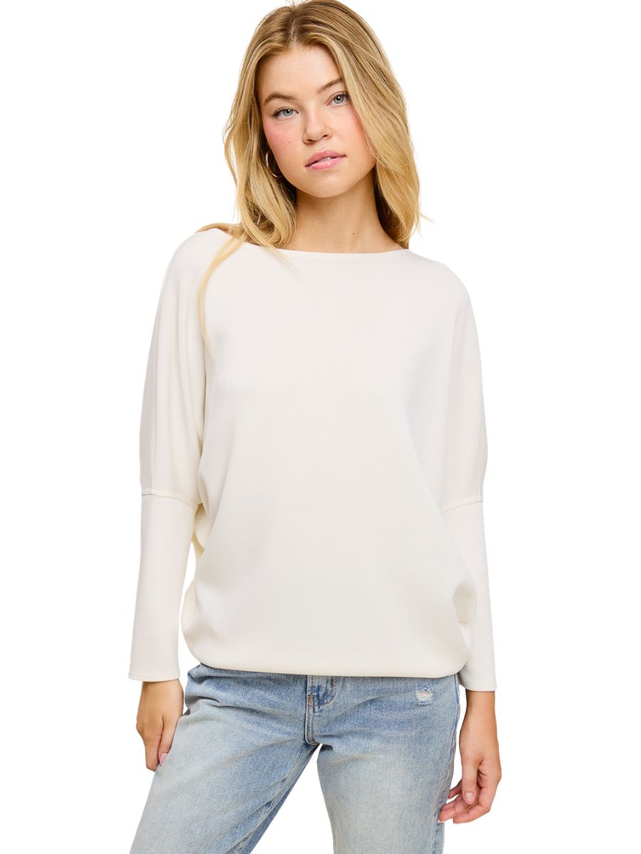 Light off-white long-sleeve sweater paired with light-wash denim jeans on a model against white background.