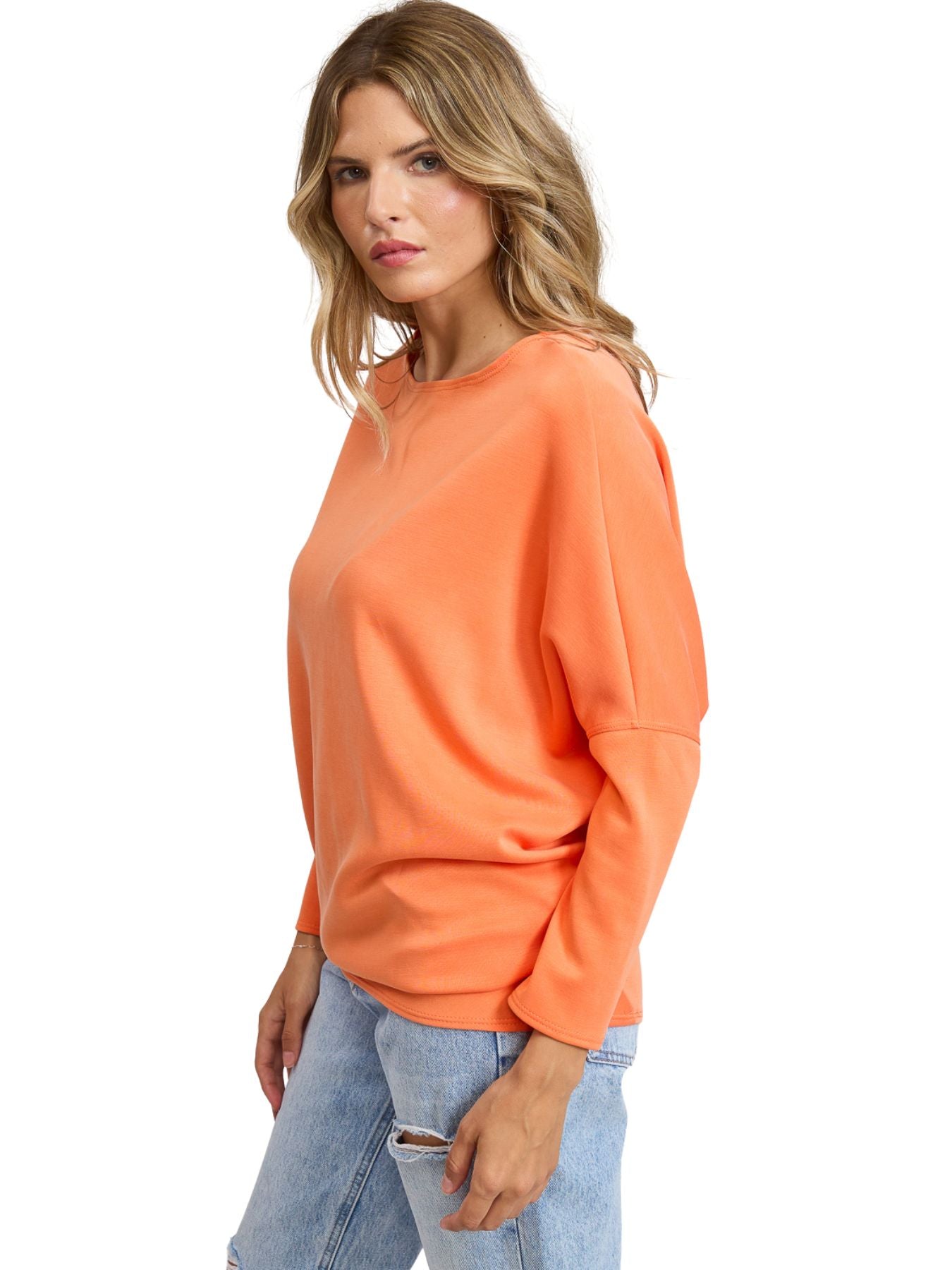 Orange Julie Modal Dolman Top by Jolie Inc., featuring relaxed fit and soft fabric, paired with distressed light denim jeans.