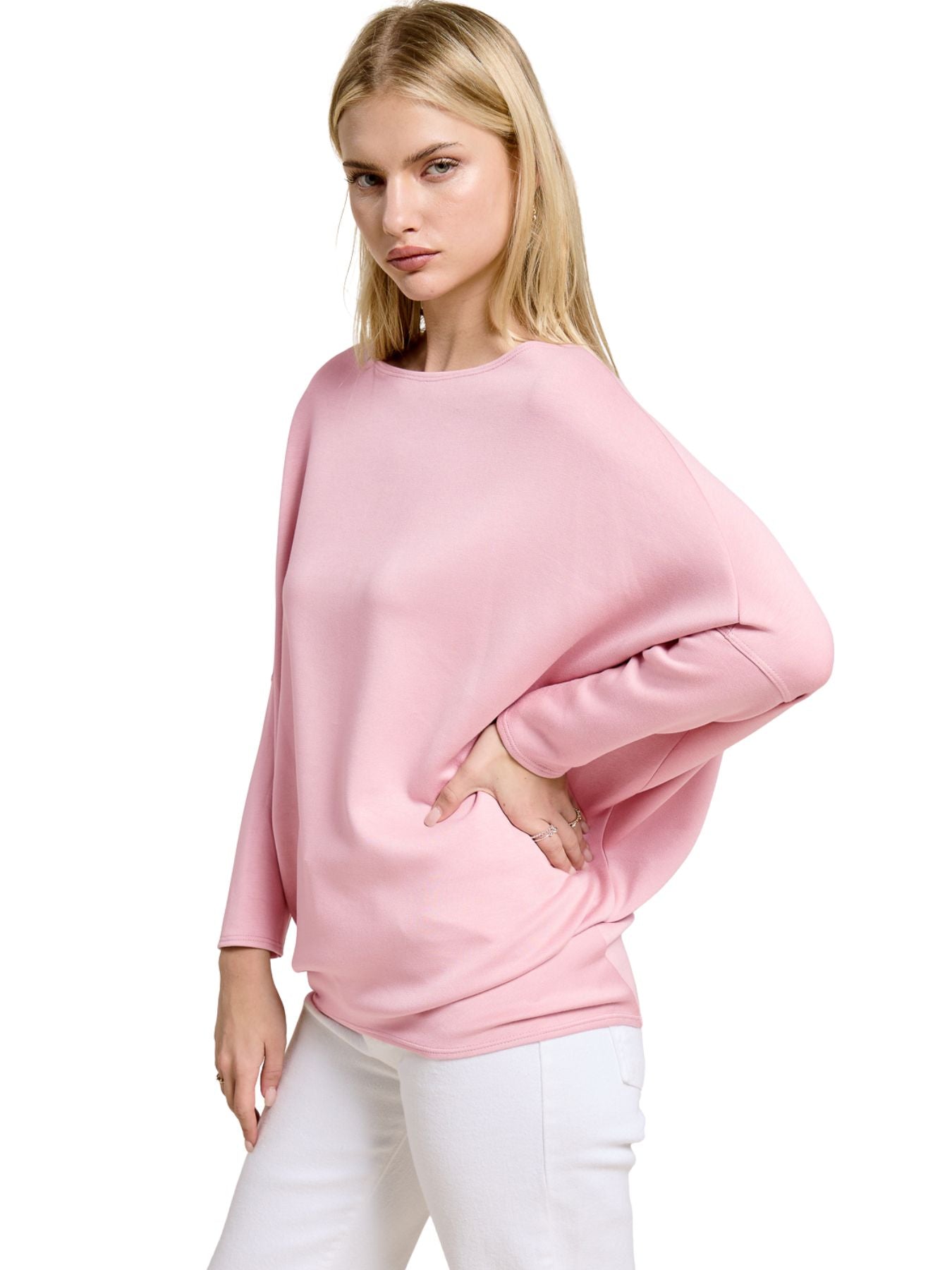 Light pink oversized sweater with long sleeves paired with white pants on a neutral background.