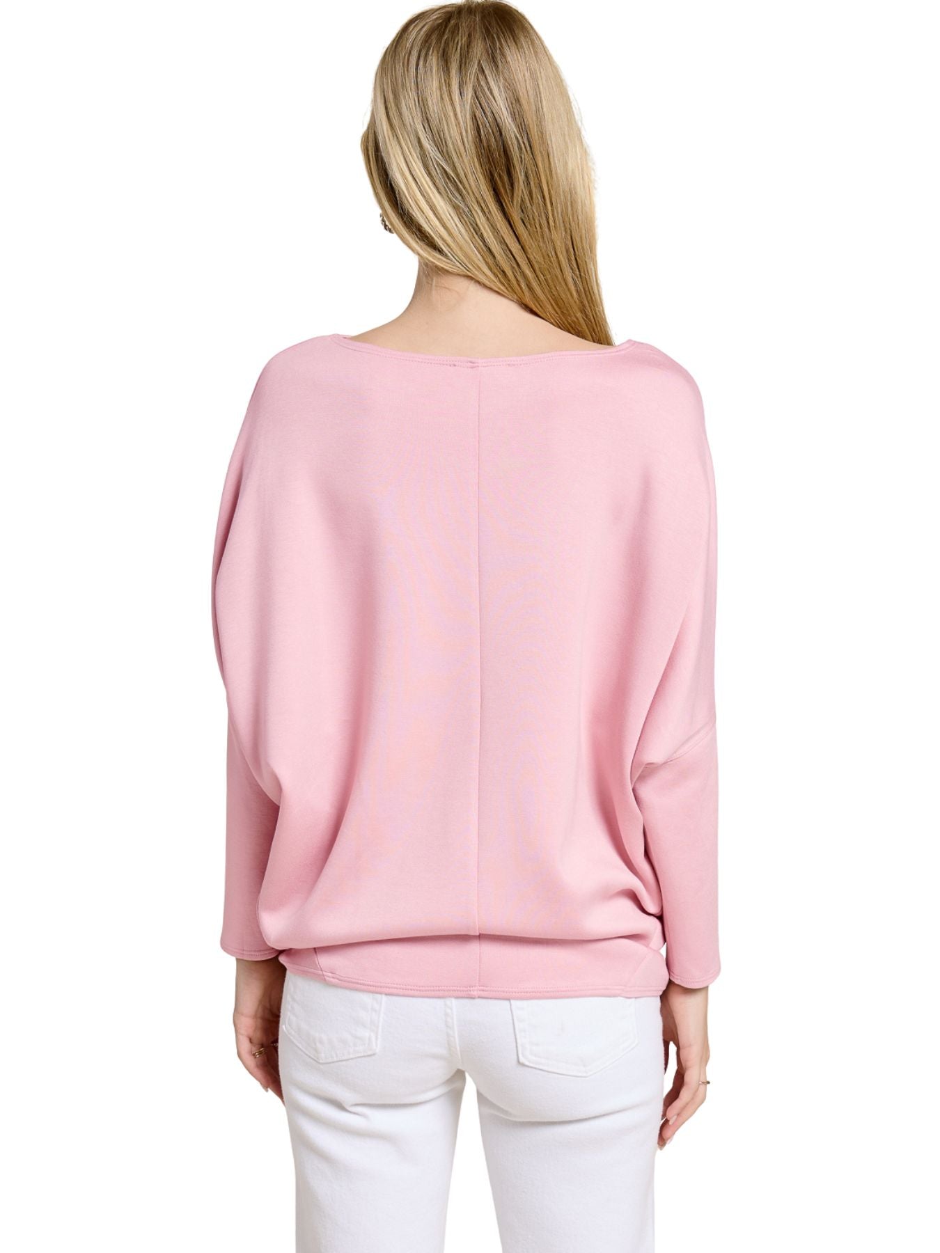 Back view of a loose-fitting pink long-sleeve top paired with white pants on a light background