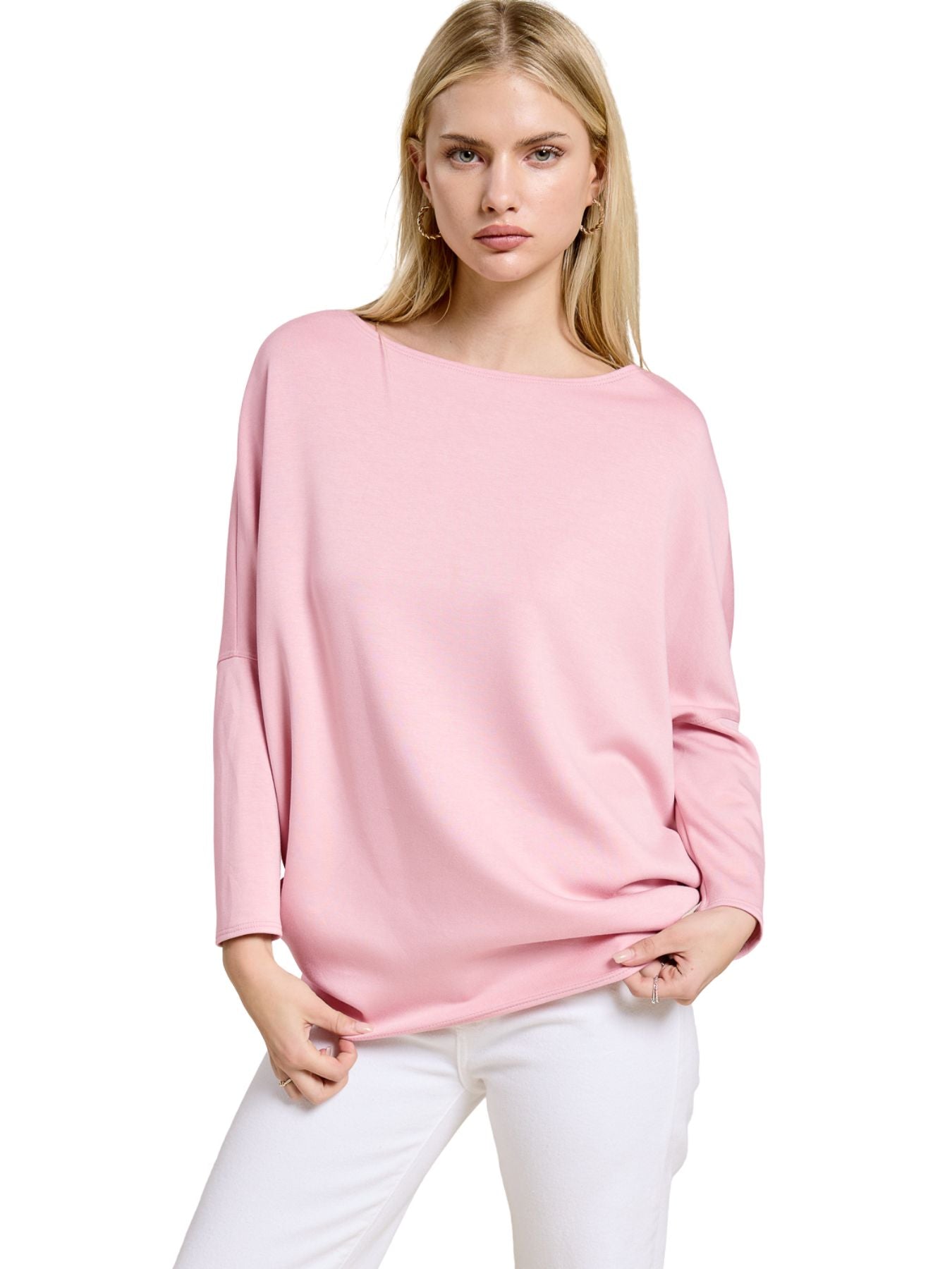 Light pink loose-fit long sleeve top paired with white pants against a white background.