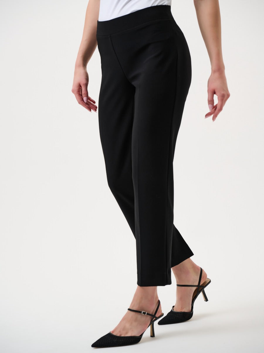 Close-up of black tailored ankle-length pants paired with black heeled slingback shoes on a person against a white background