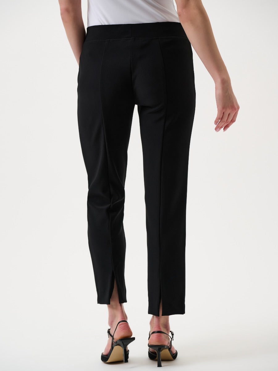 Rear view of black tailored ankle pants with back slits worn with black heeled sandals and a white top
