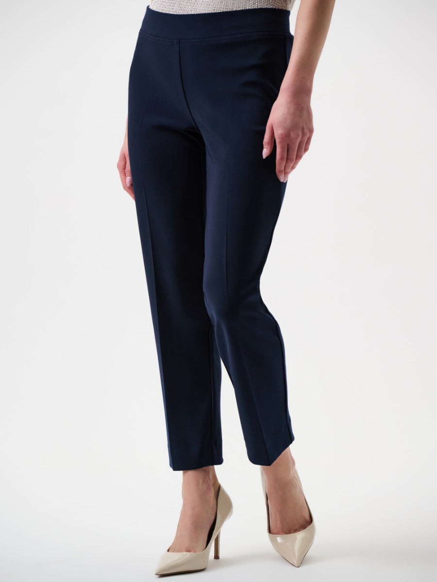 Navy tailored slim-fit pants paired with beige pointed-toe high heels on a white background