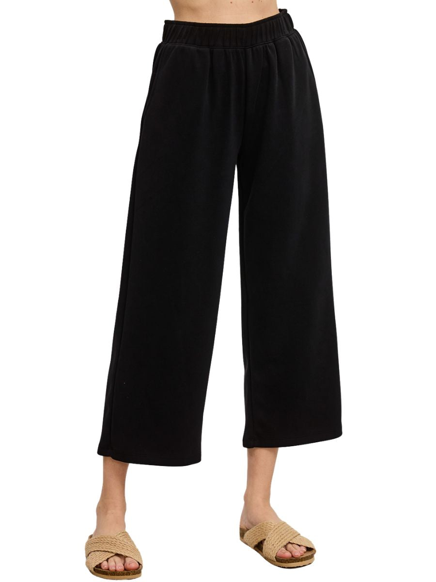 Black wide-leg cropped pants with elastic waistband paired with beige woven slip-on sandals