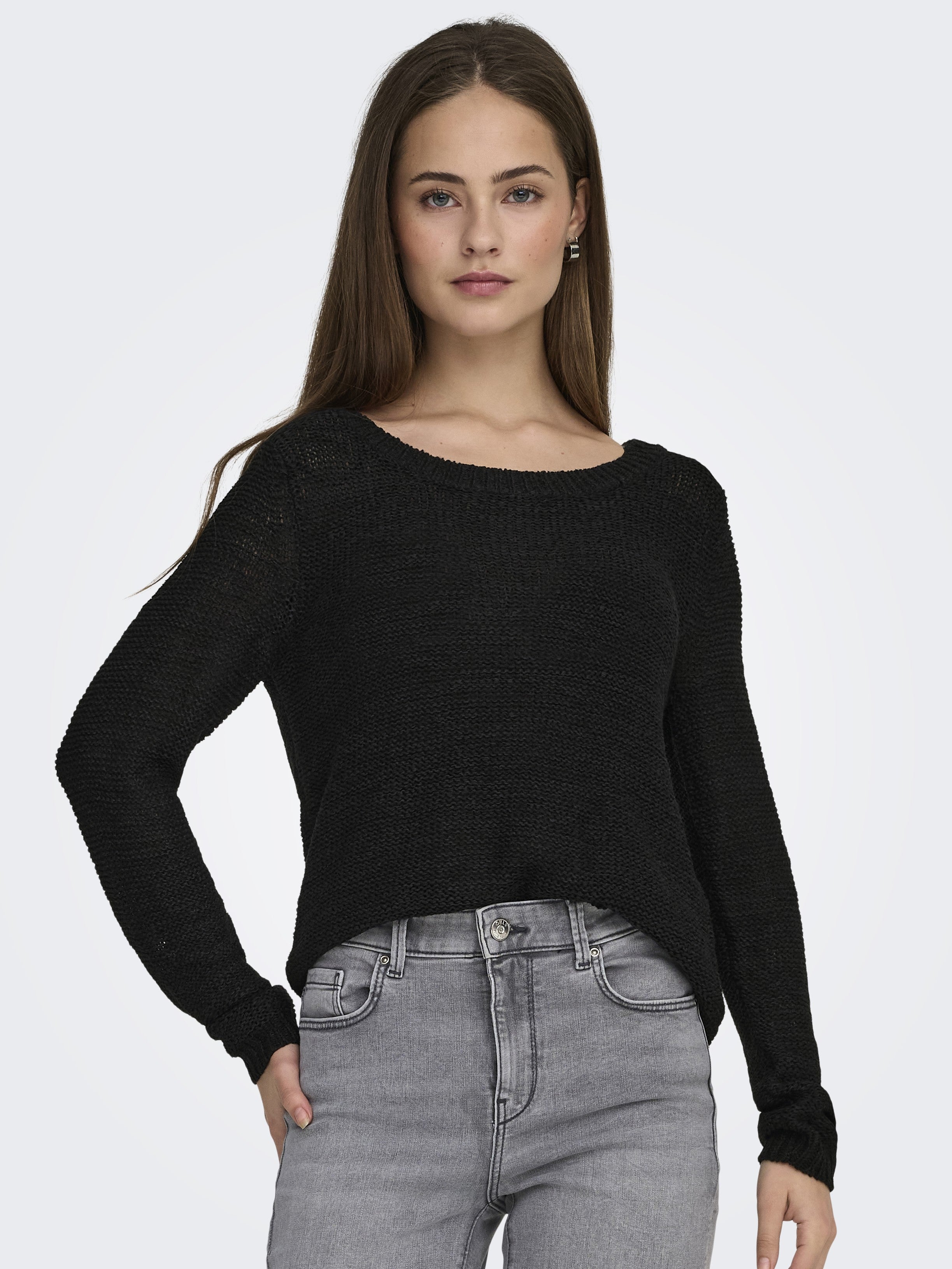 ONLY Geena Loose Knit Crew Sweater in black by Only, featuring a relaxed fit and long sleeves, styled with light gray denim jeans.