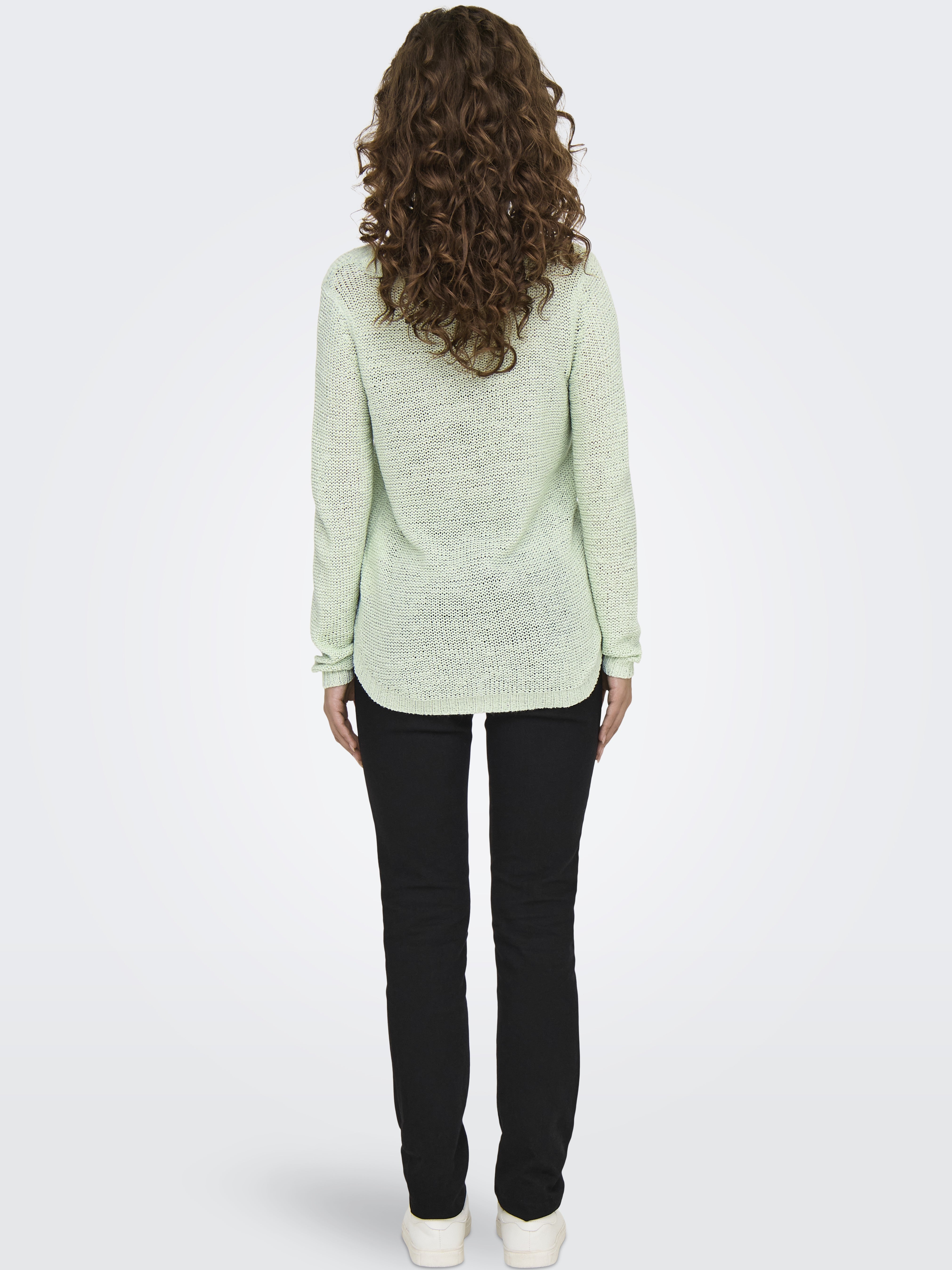 Light green knit sweater paired with black pants and white shoes, shown from the back on a plain background.