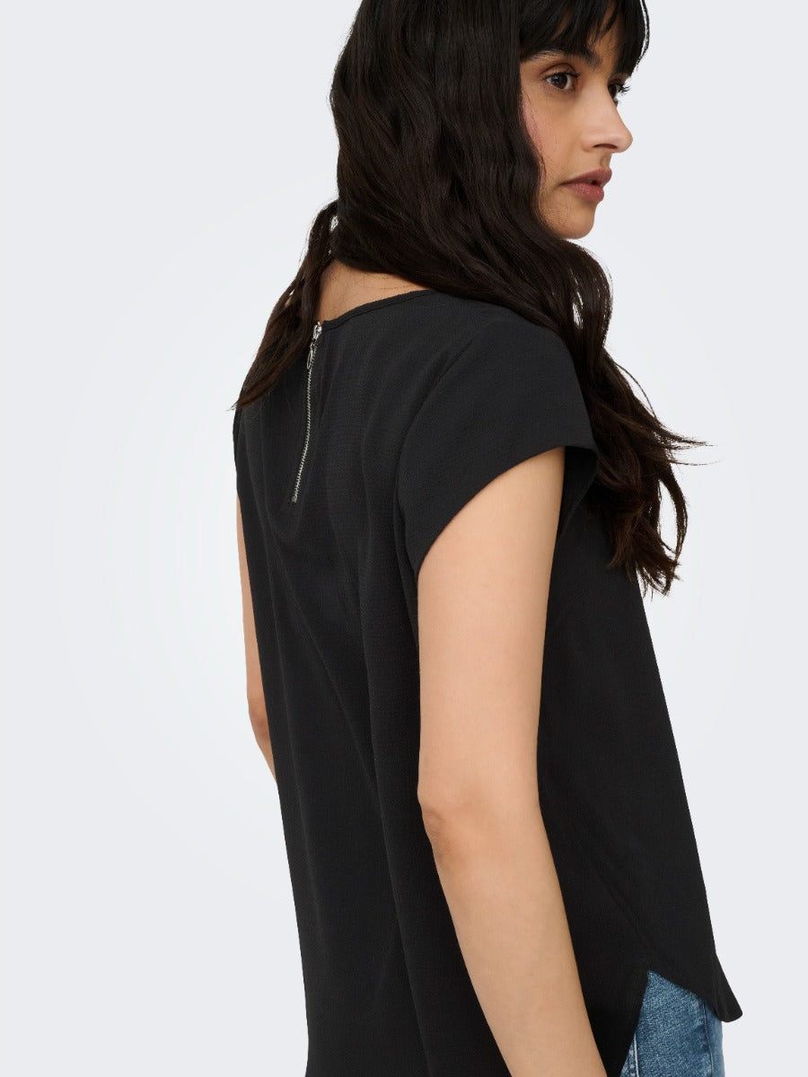 Side view of a person wearing a black short-sleeve top with a back zipper detail and blue jeans