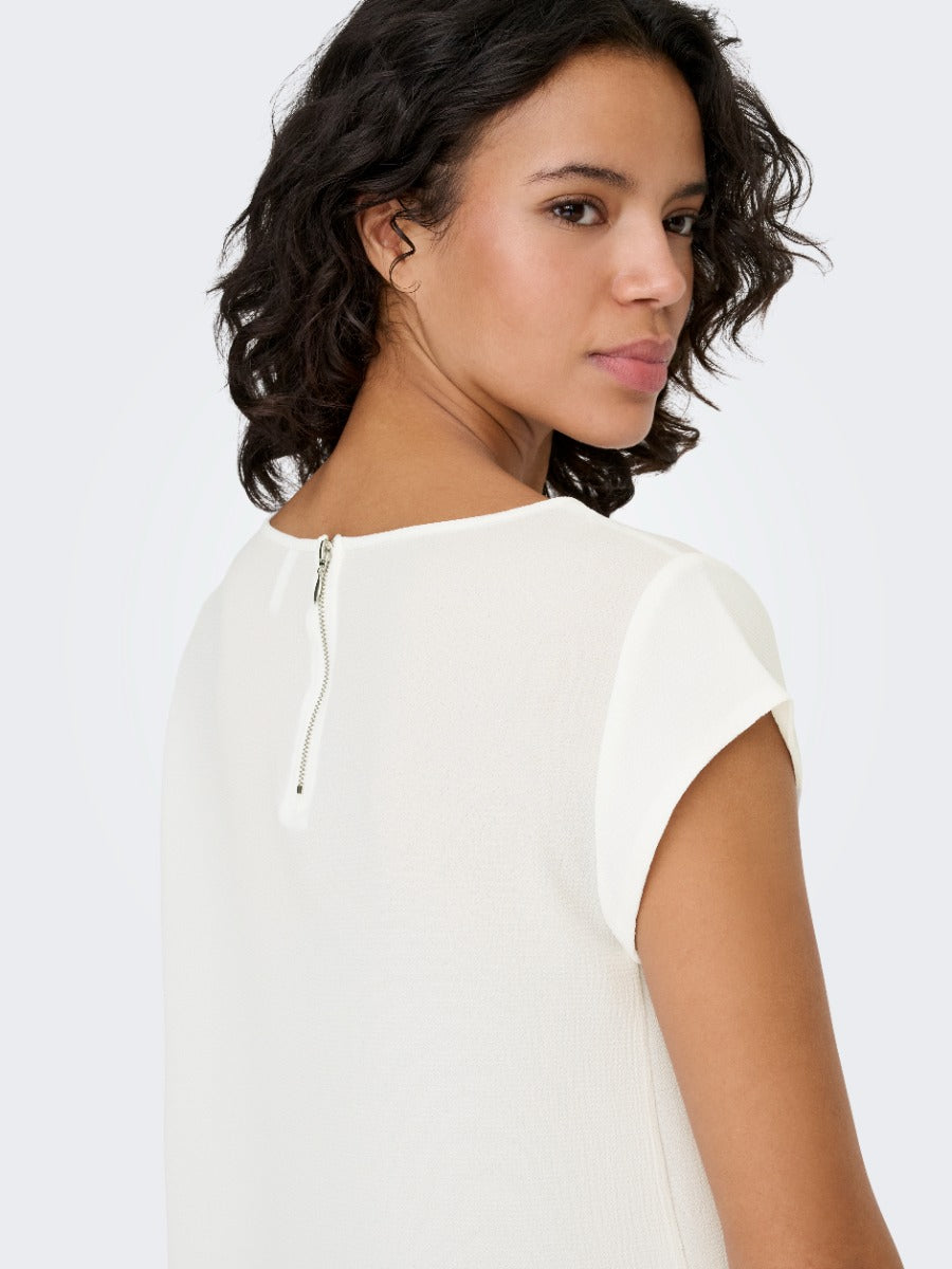 Close-up of a person in a white textured top with a visible back zipper on a plain light background