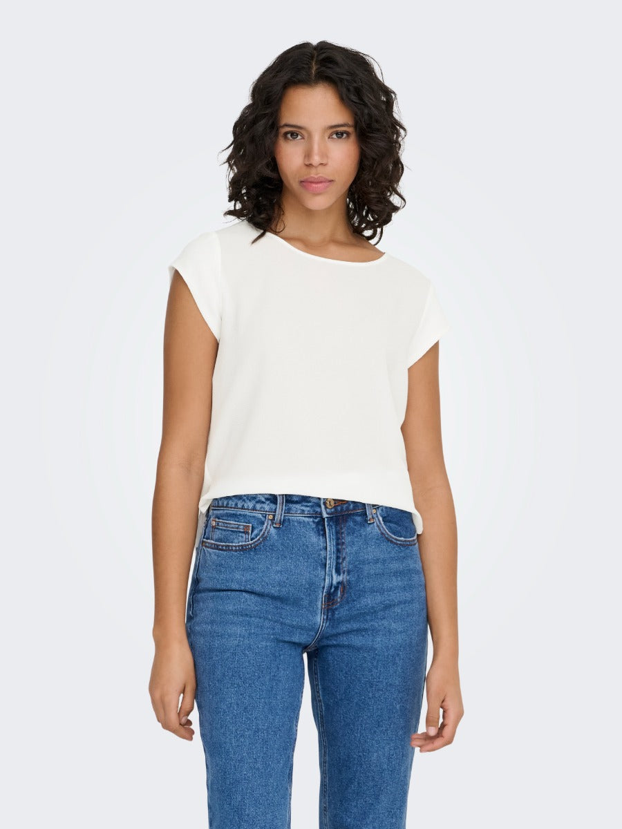 Person wearing a short-sleeve off-white top paired with high-waisted blue denim jeans against a white background