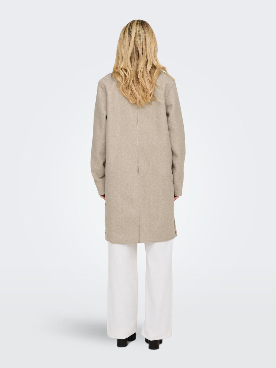 Back view of a beige ONLY Carrie Bonded 3 Button Coat by Only worn over white pants with black shoes.
