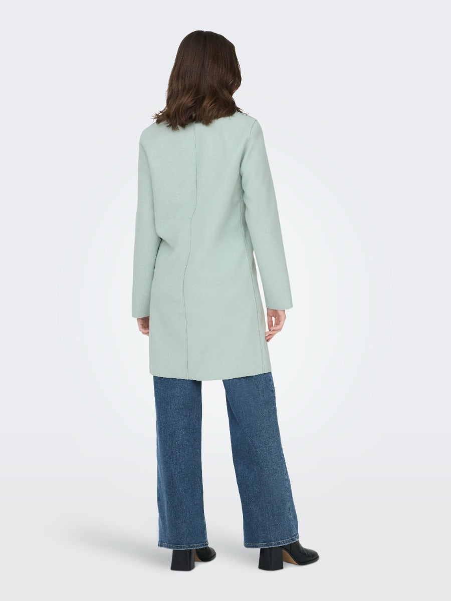 Back view of a light green ONLY Carrie Bonded 3 Button Coat by Only paired with blue denim jeans and black shoes.