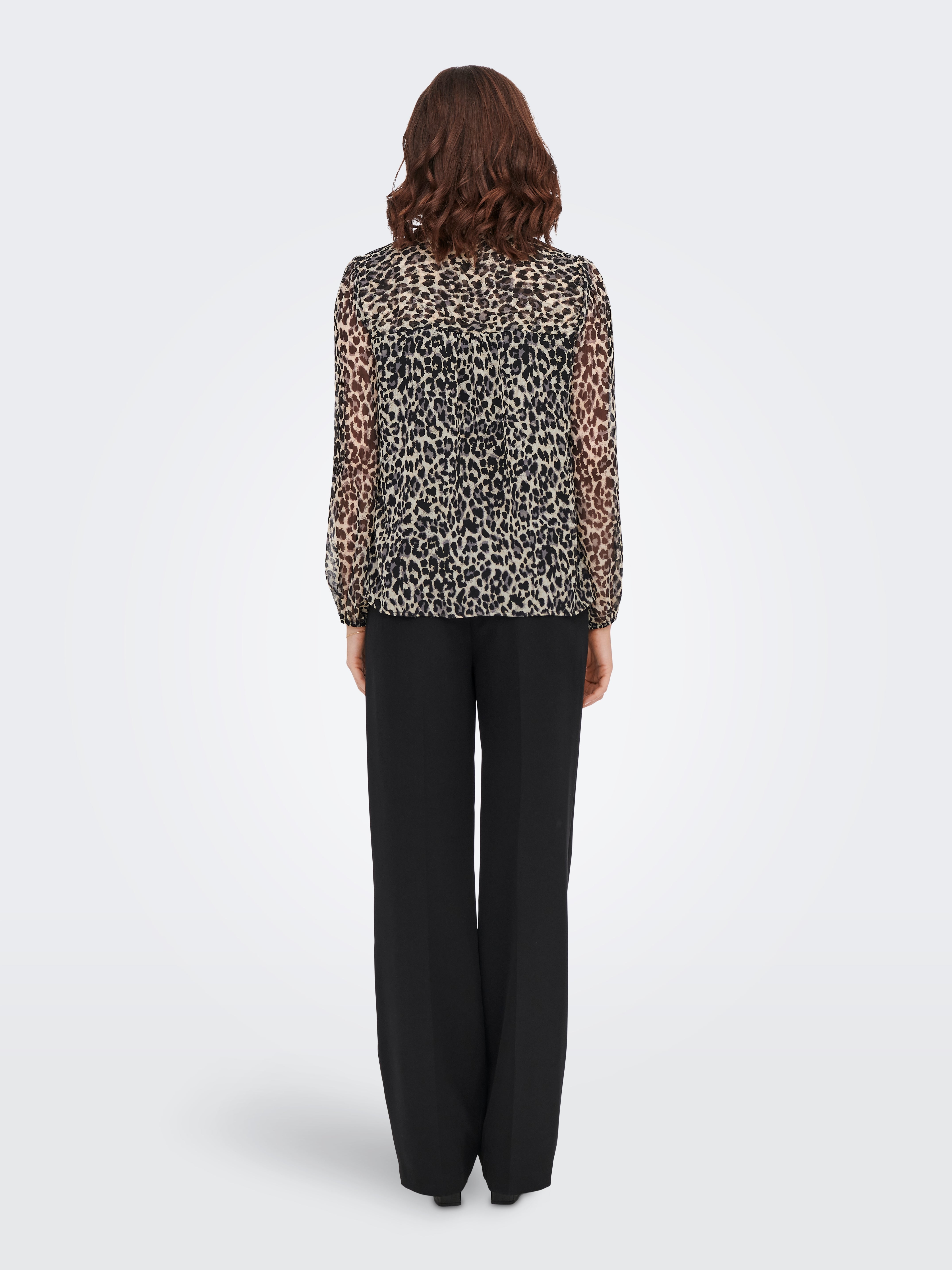 Back view of a sheer long-sleeve leopard print top paired with black wide-leg trousers on a gray background.