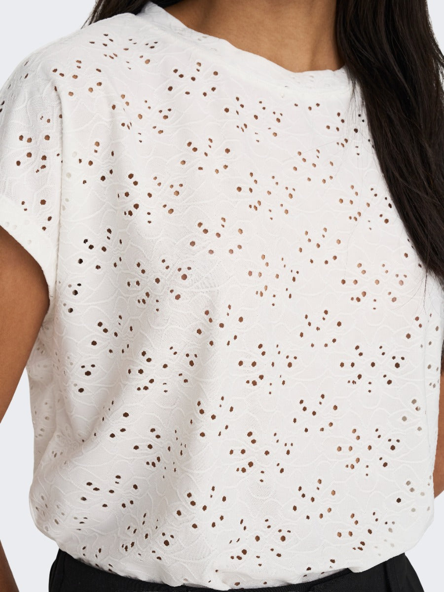 White eyelet lace short sleeve top with delicate floral cutout detailing on a light fabric