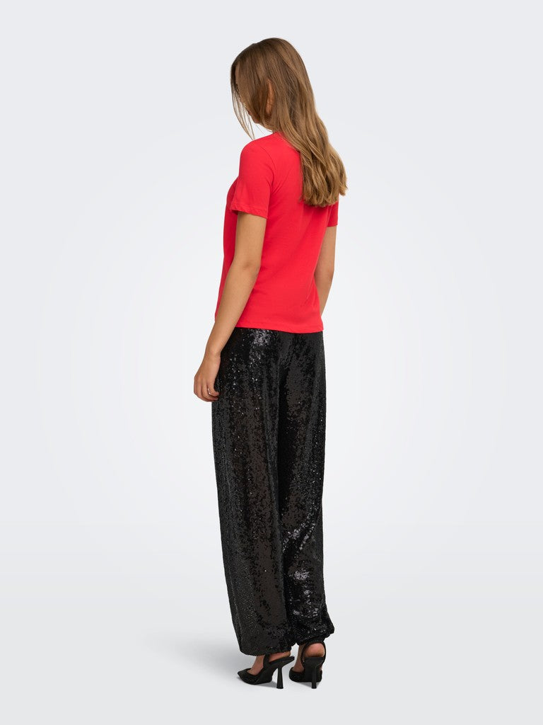 Back view of a figure in a red short sleeve top, black sequined wide leg trousers, and black heels
