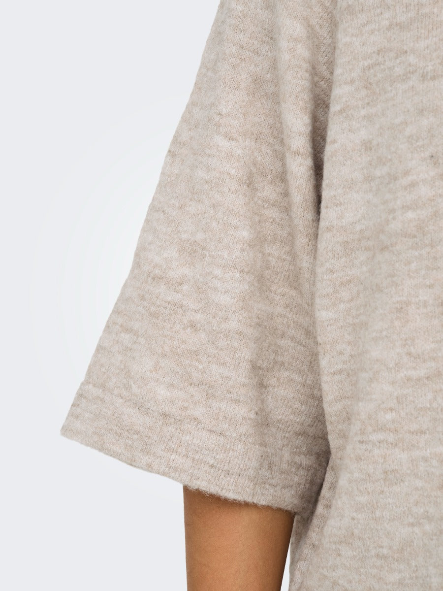 Close-up of a soft taupe knit sweater sleeve with a relaxed fit on light skin tone.