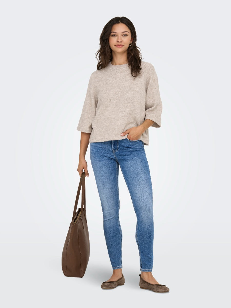 Person wearing a taupe three-quarter sleeve sweater, blue skinny jeans, brown flats, and carrying a large brown tote bag.
