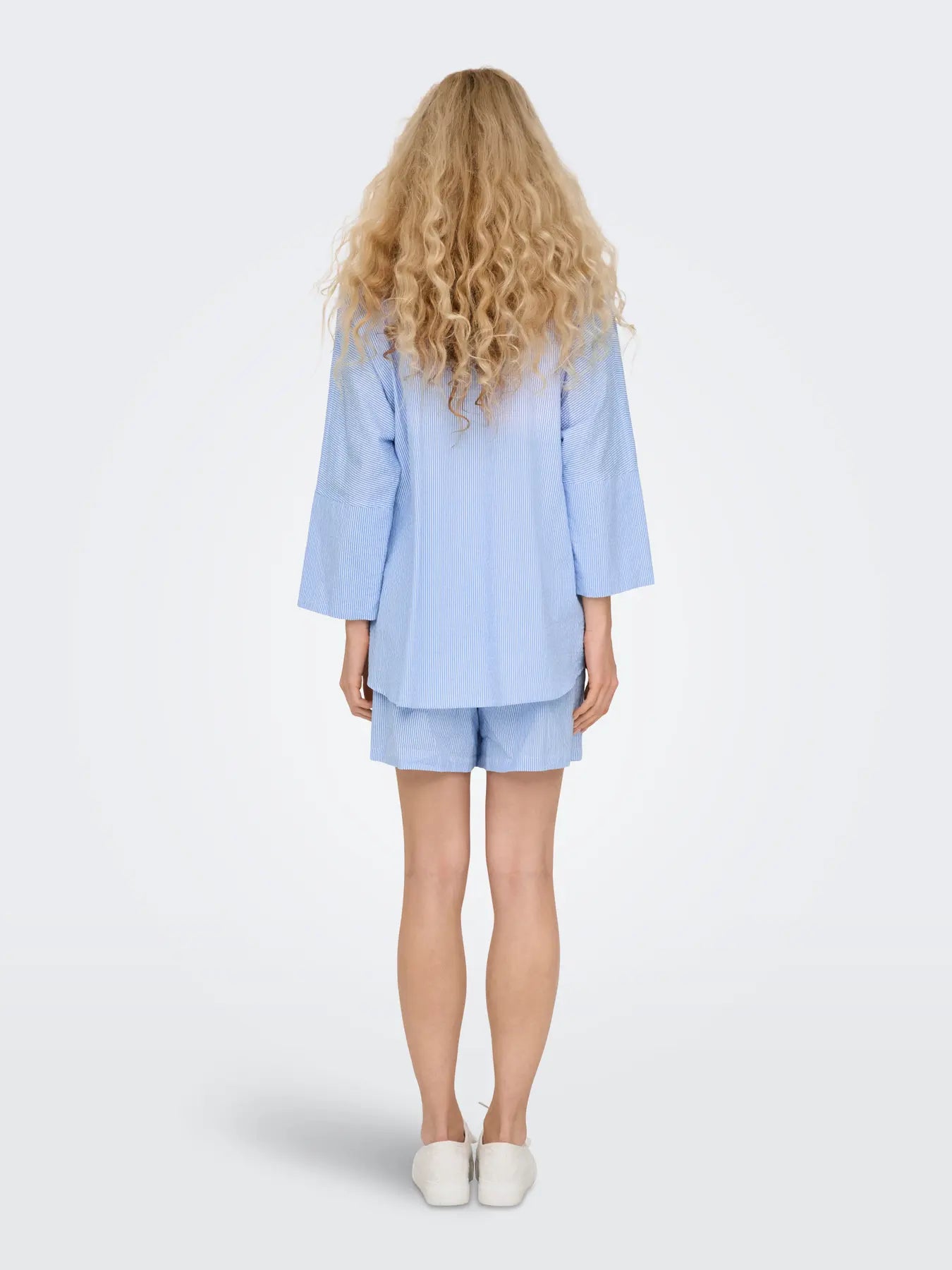 Light blue long-sleeve shirt and matching shorts paired with white slip-on shoes shown from the back.