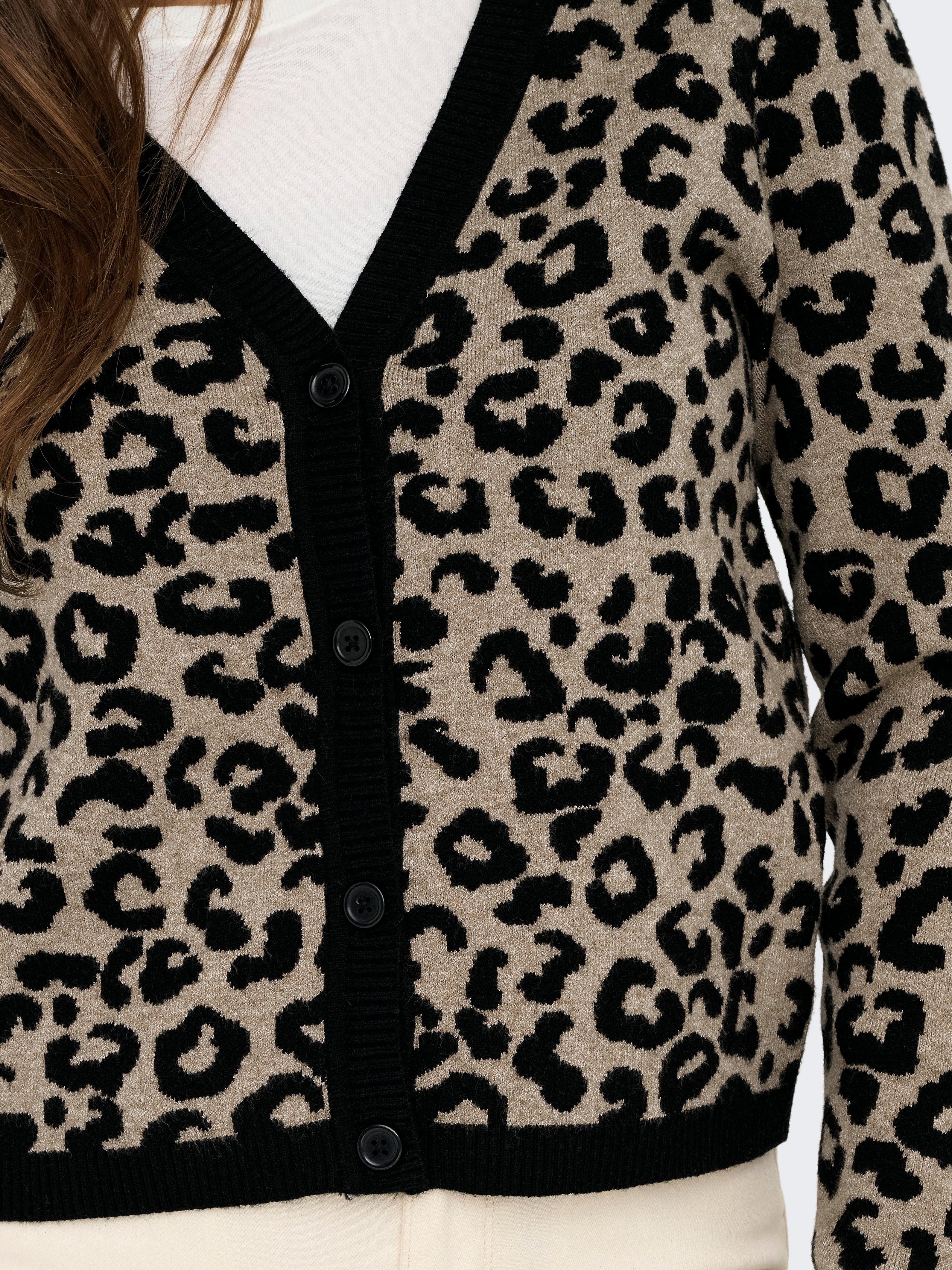 Close-up of a leopard print cardigan with black trim and buttons over a white top.