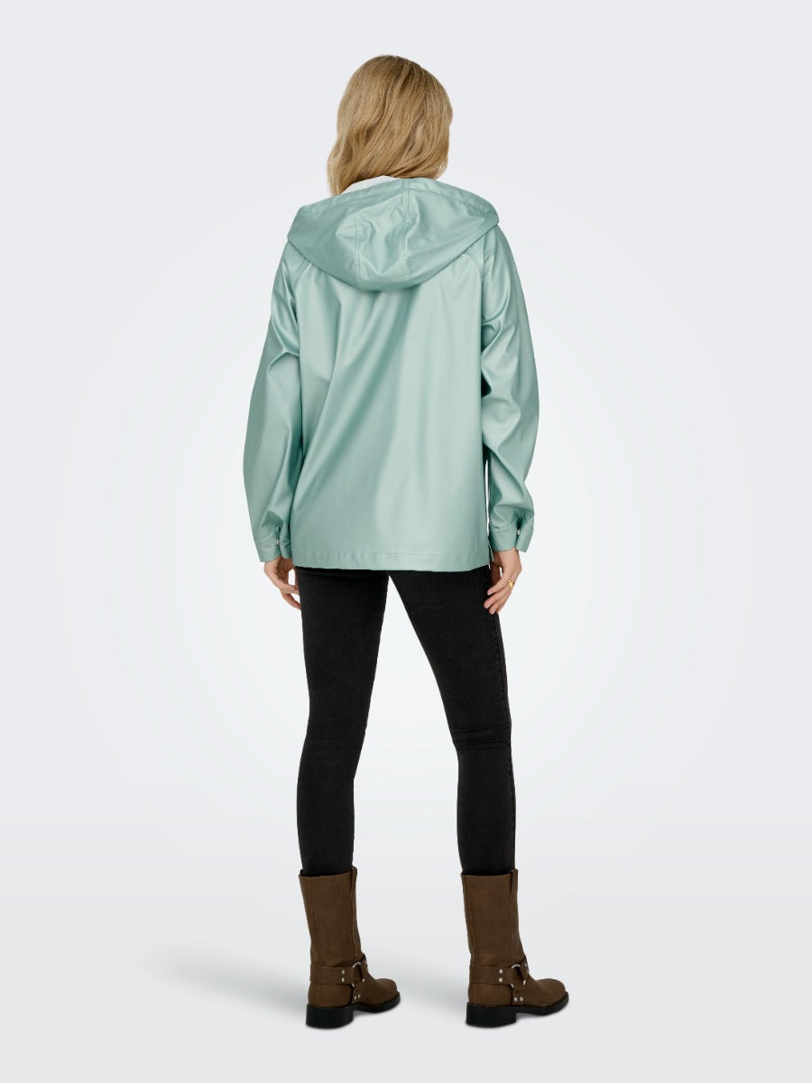 Back view of light green ONLY Leben Shiny Hooded Rain Jacket by Only styled with black pants and brown boots