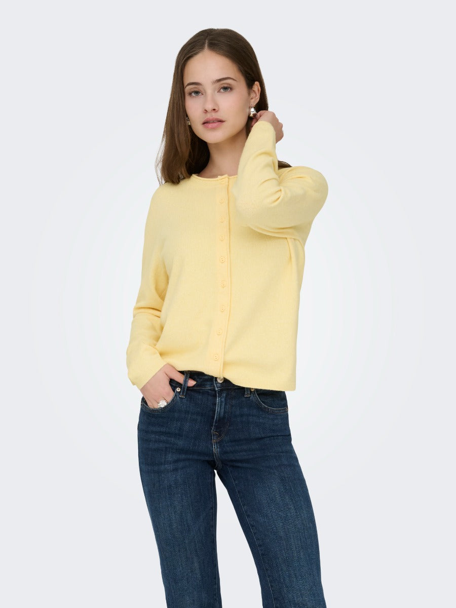 Light yellow button-up cardigan paired with dark blue denim jeans on a model against a plain background.