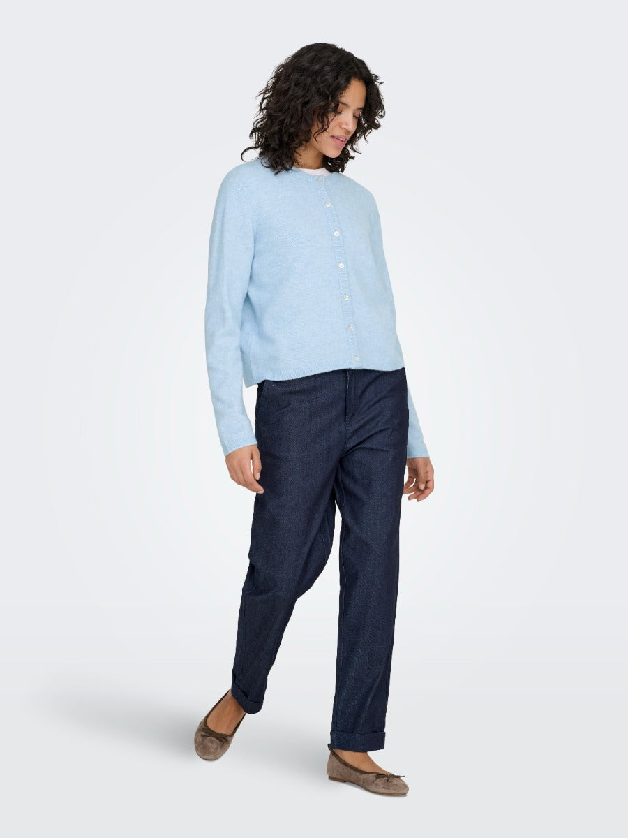 Light blue buttoned sweater paired with dark denim pants and brown flat shoes on a neutral background