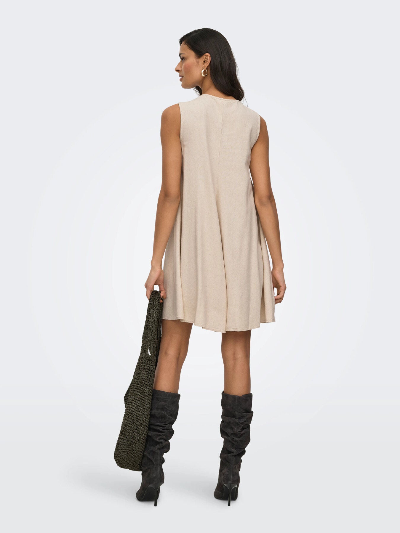 Back view of sleeveless beige Jacqueline De Yong Linen Dress styled with black boots and a textured bag.