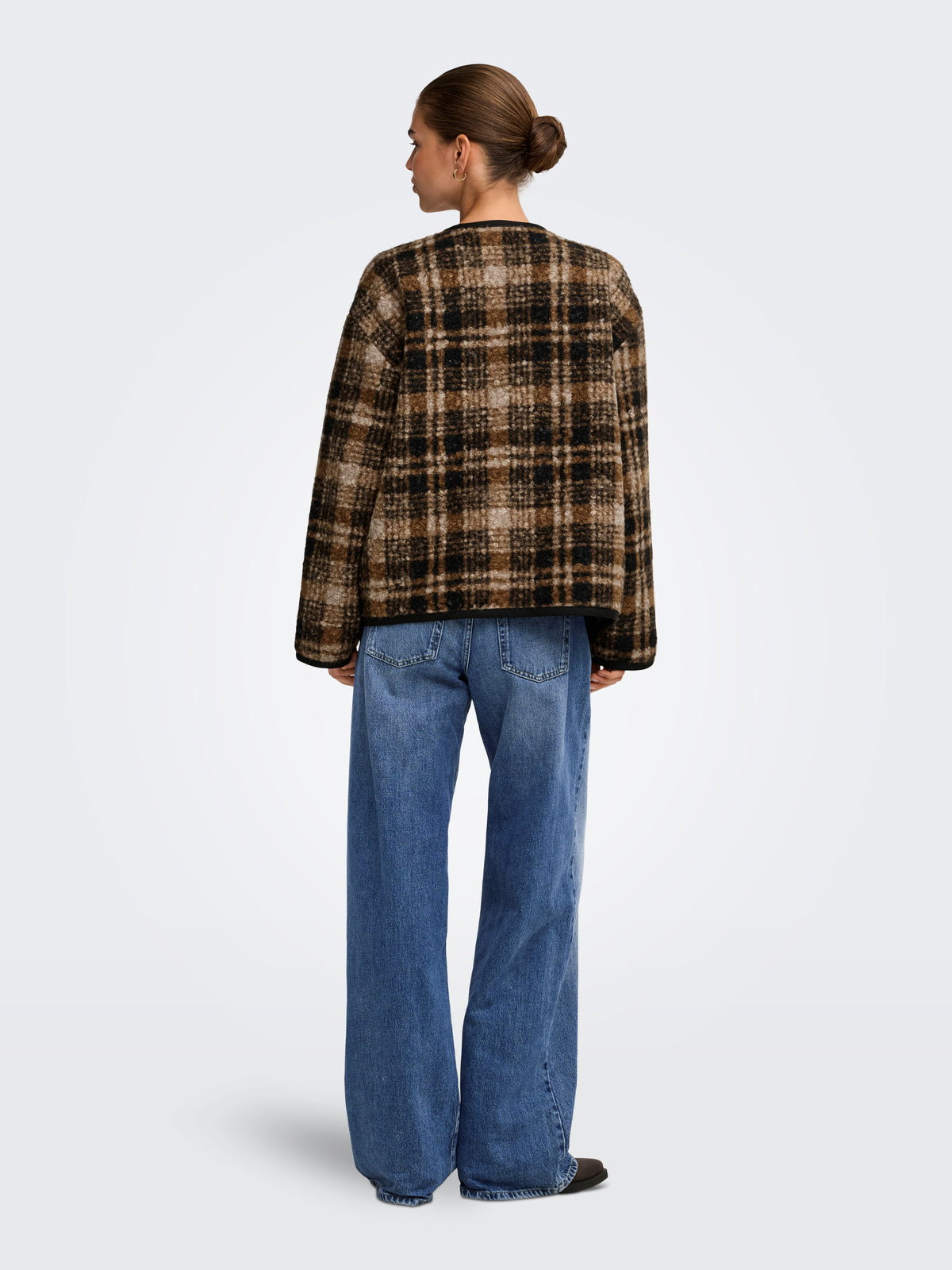 Back view of a model in a brown plaid jacket and wide-leg blue denim jeans