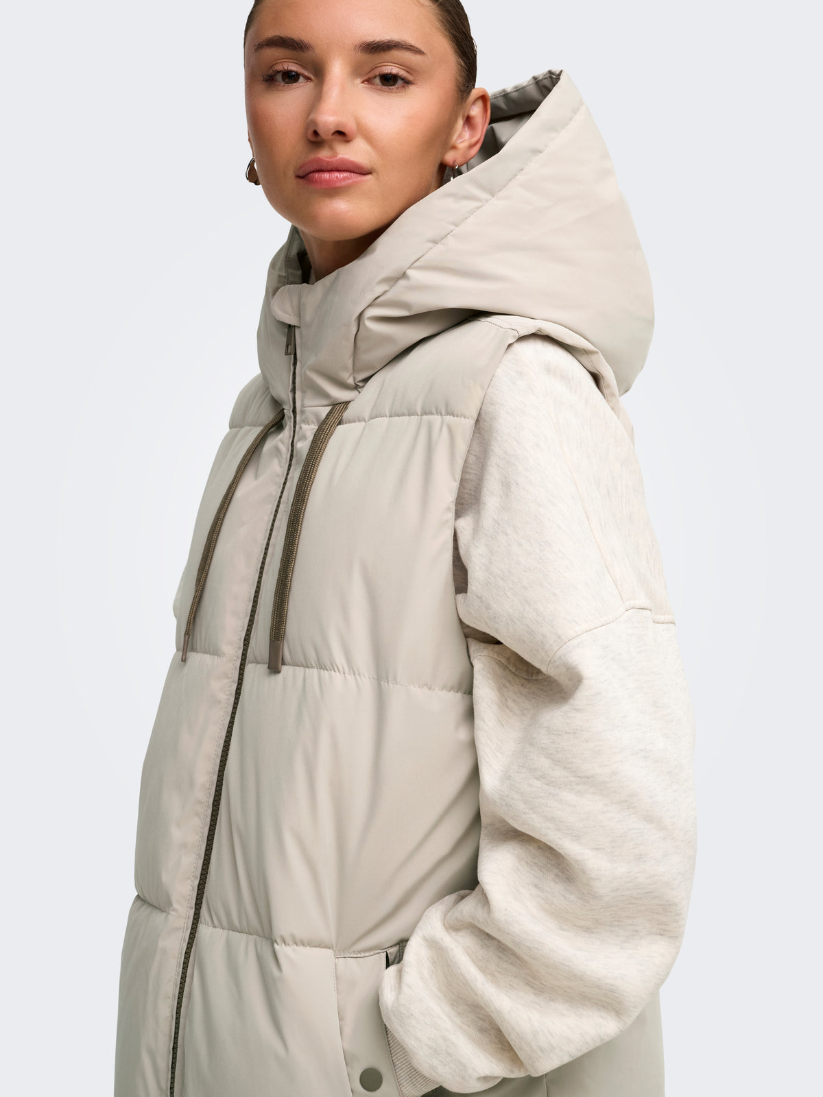 Cream hooded puffer vest layered over a light sweater
