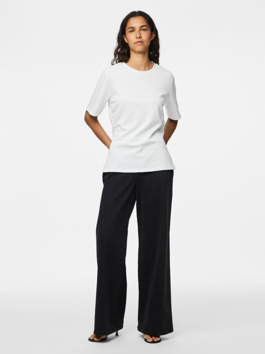 Individual wearing a simple white short-sleeve top paired with wide-leg black pants and black open-toe heels
