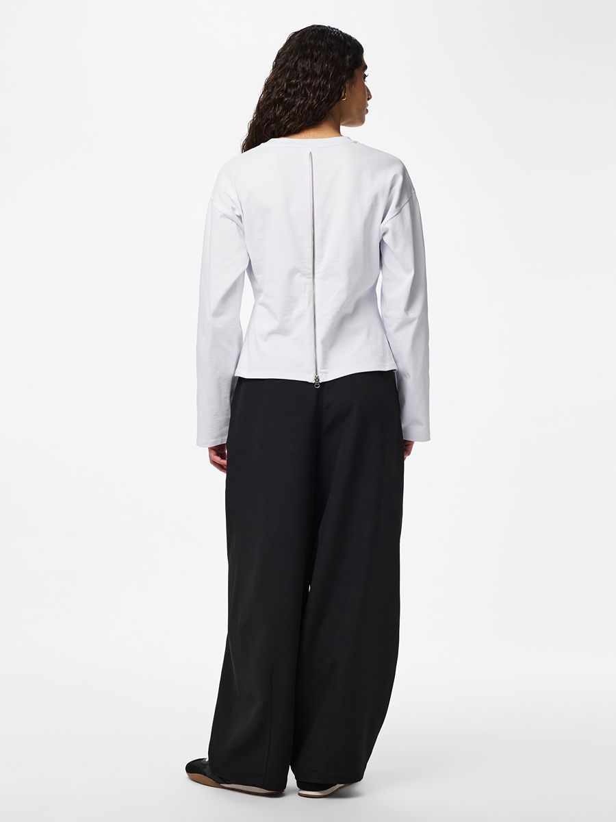 Amy Back Zip Long Sleeve Top by Pieces in white with back zipper detail, paired with wide black pants.