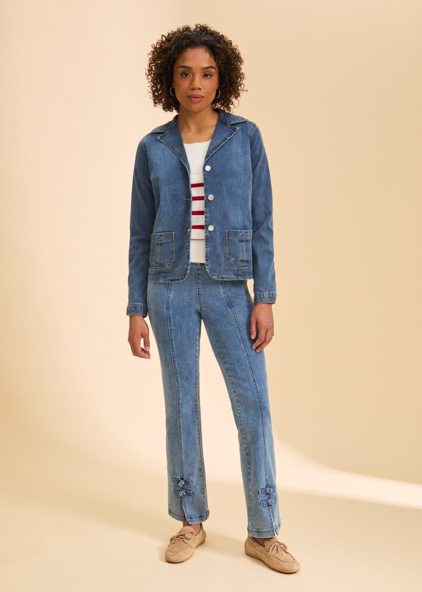 Person standing wearing a blue denim jacket with front pockets over a striped top and matching denim pants with bows near the ankles.