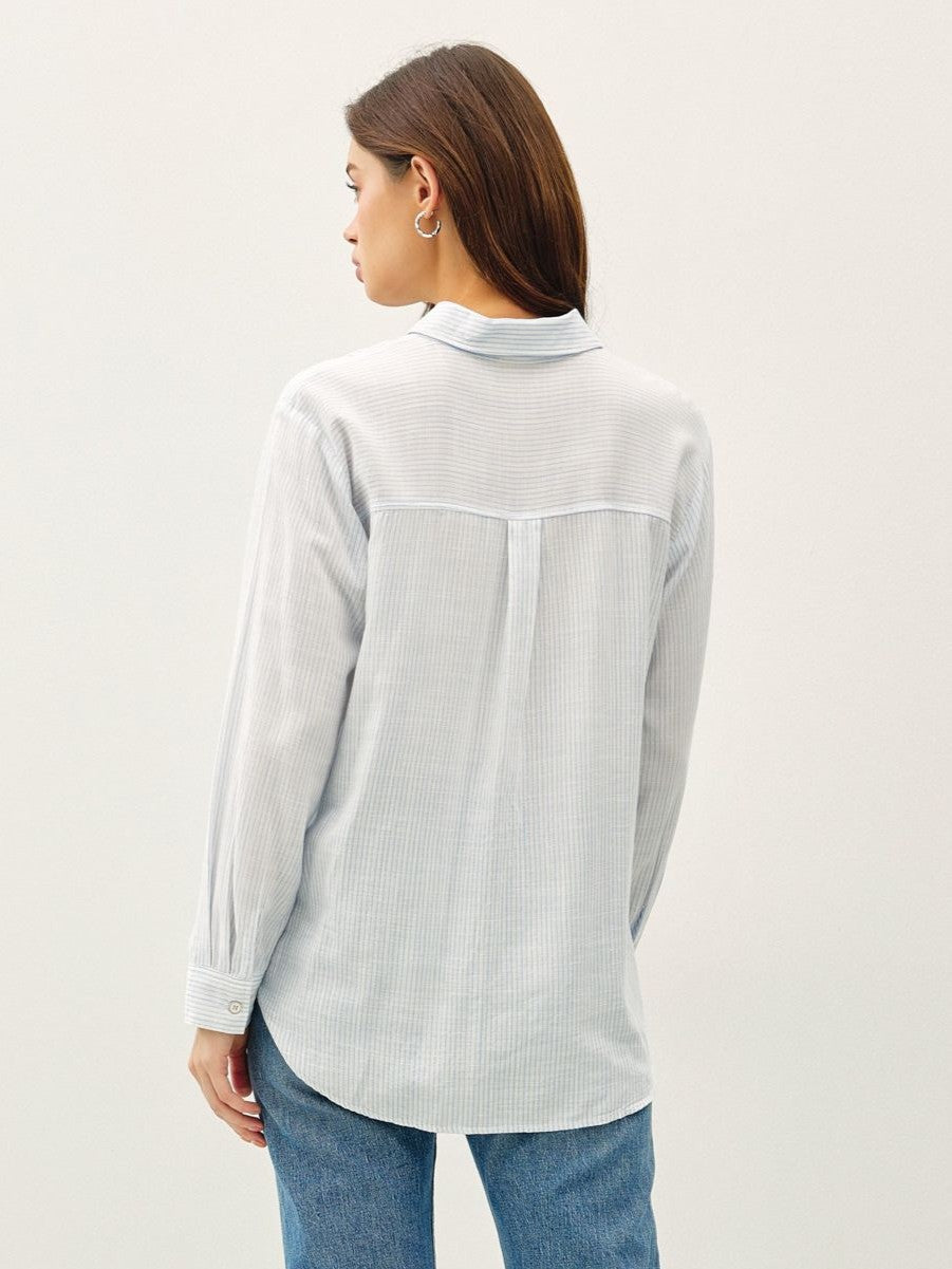 Light blue long-sleeve shirt with subtle stripes paired with blue denim jeans, viewed from the back.