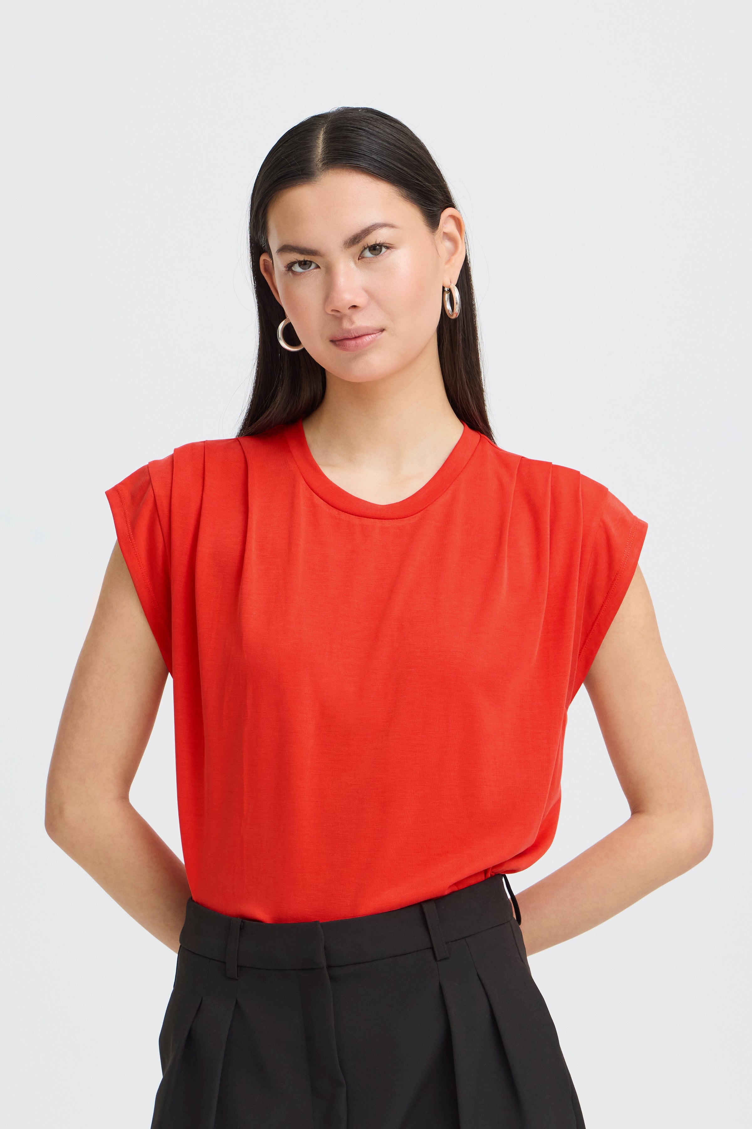 Ichi Lisken Top in bright red worn with black high-waisted tailored pants in a minimalist studio setting