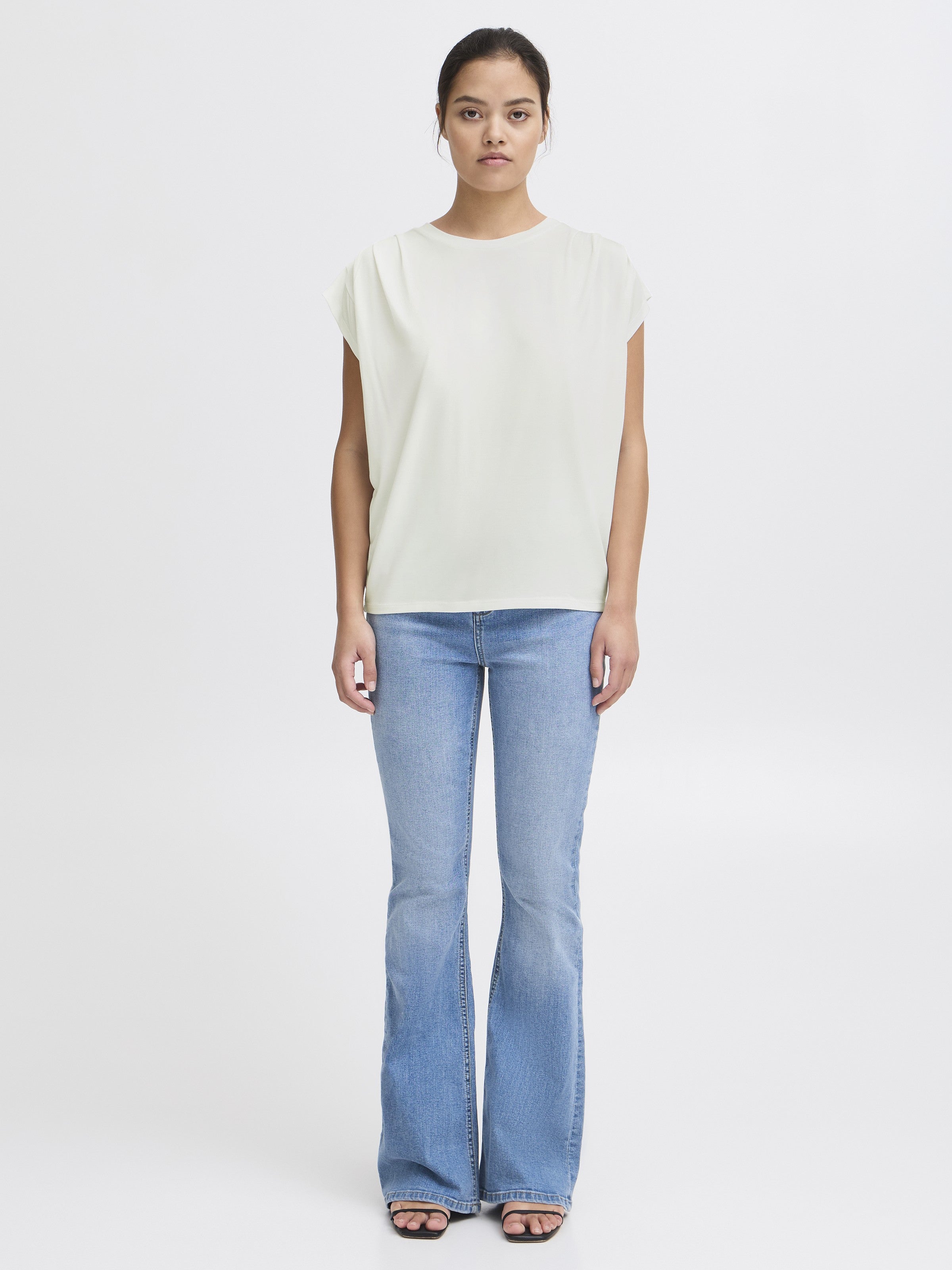 Ichi Lisken Top in white paired with light blue flared denim jeans by Ichi, styled with open-toe sandals