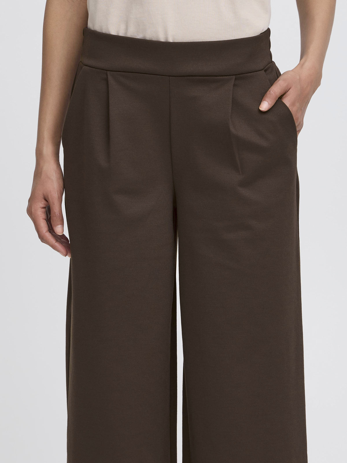Dark brown wide-leg trousers with a high waistband and front pockets against a light background