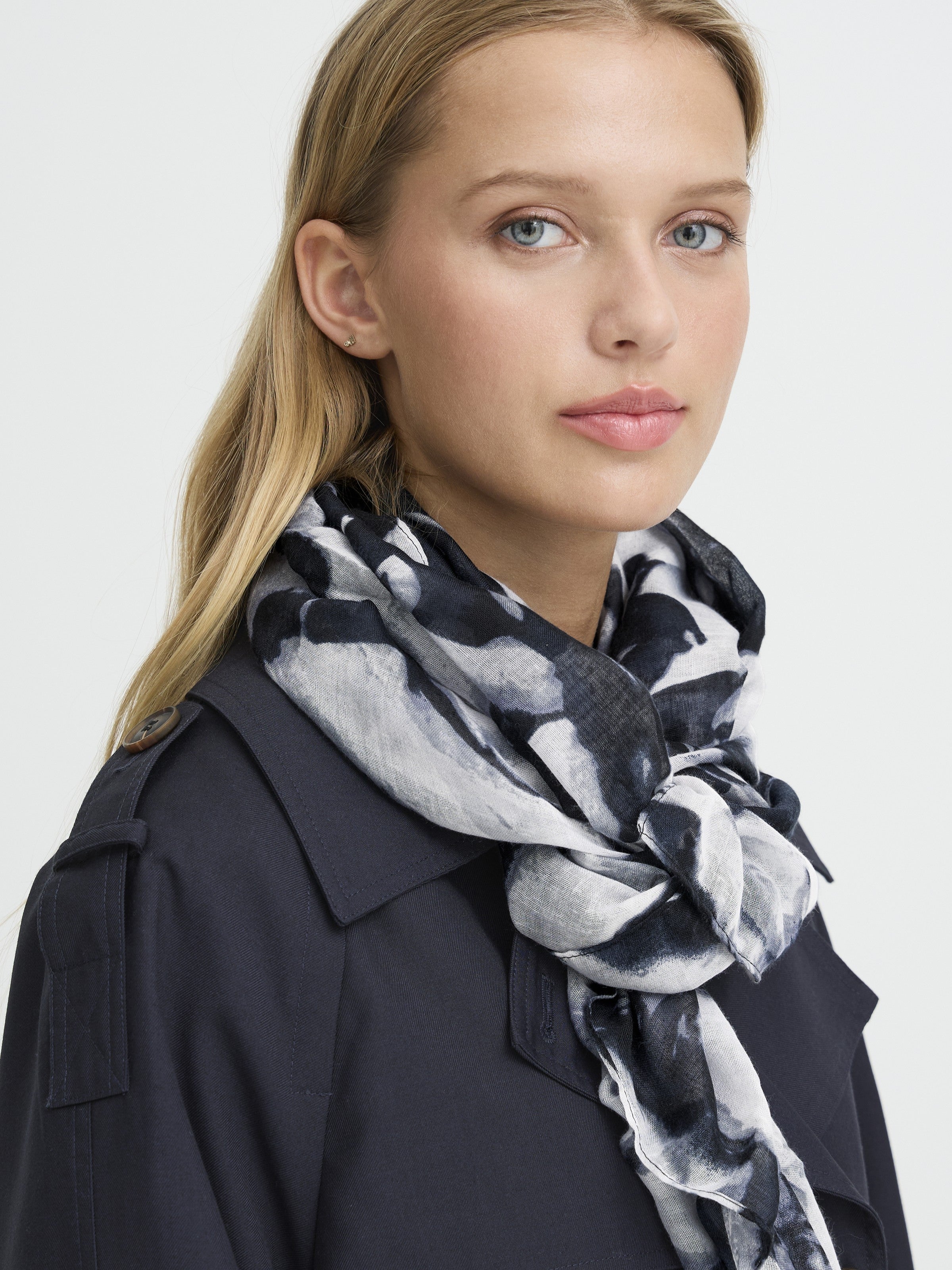 Close-up of a person wearing an Ichi Anita Floral Scarf in black and white, styled with a dark jacket accessory