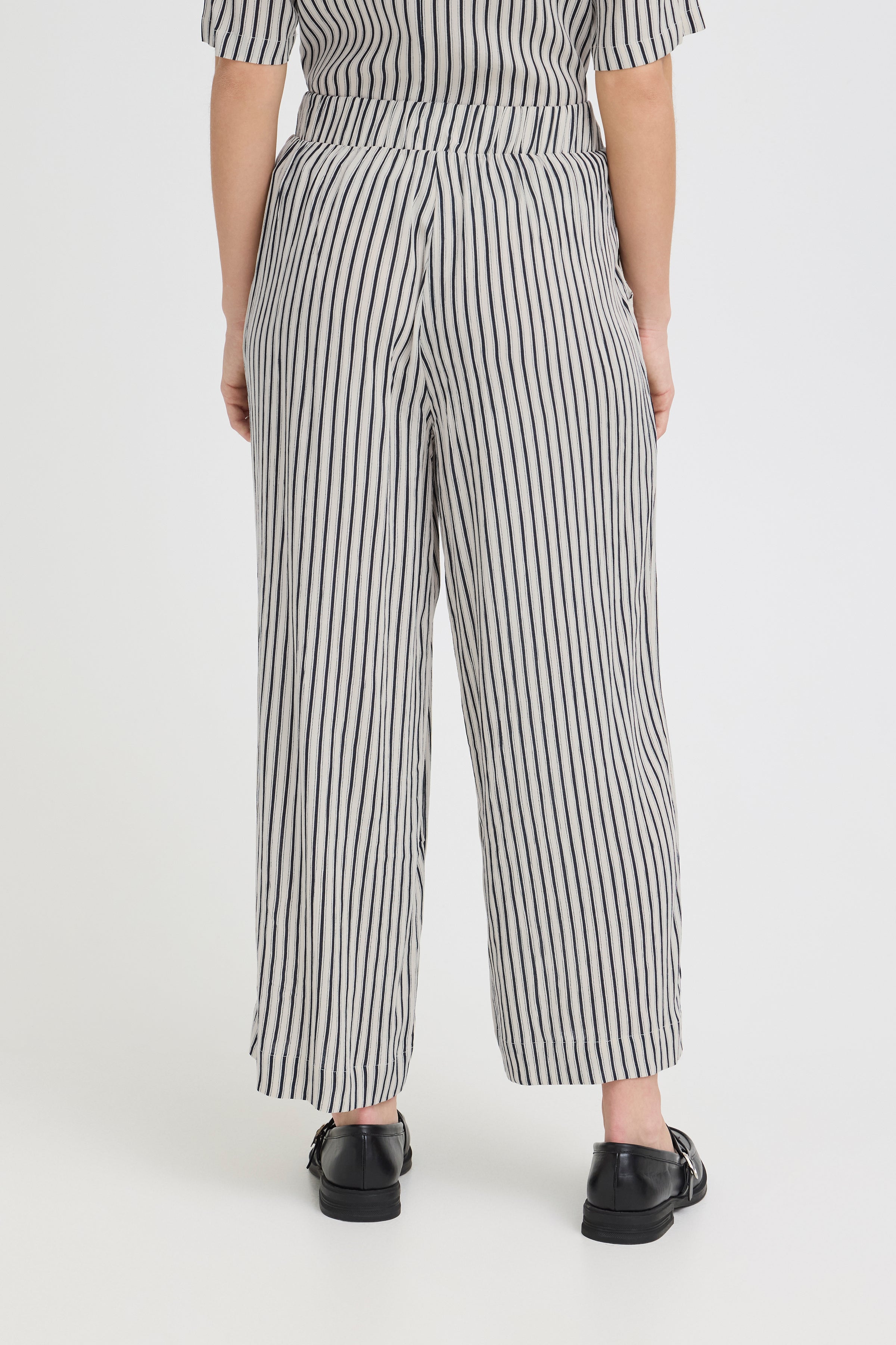 Ichi Marrakech Cropped Trousers in vertical black and white stripes styled with black shoes, viewed from the back.