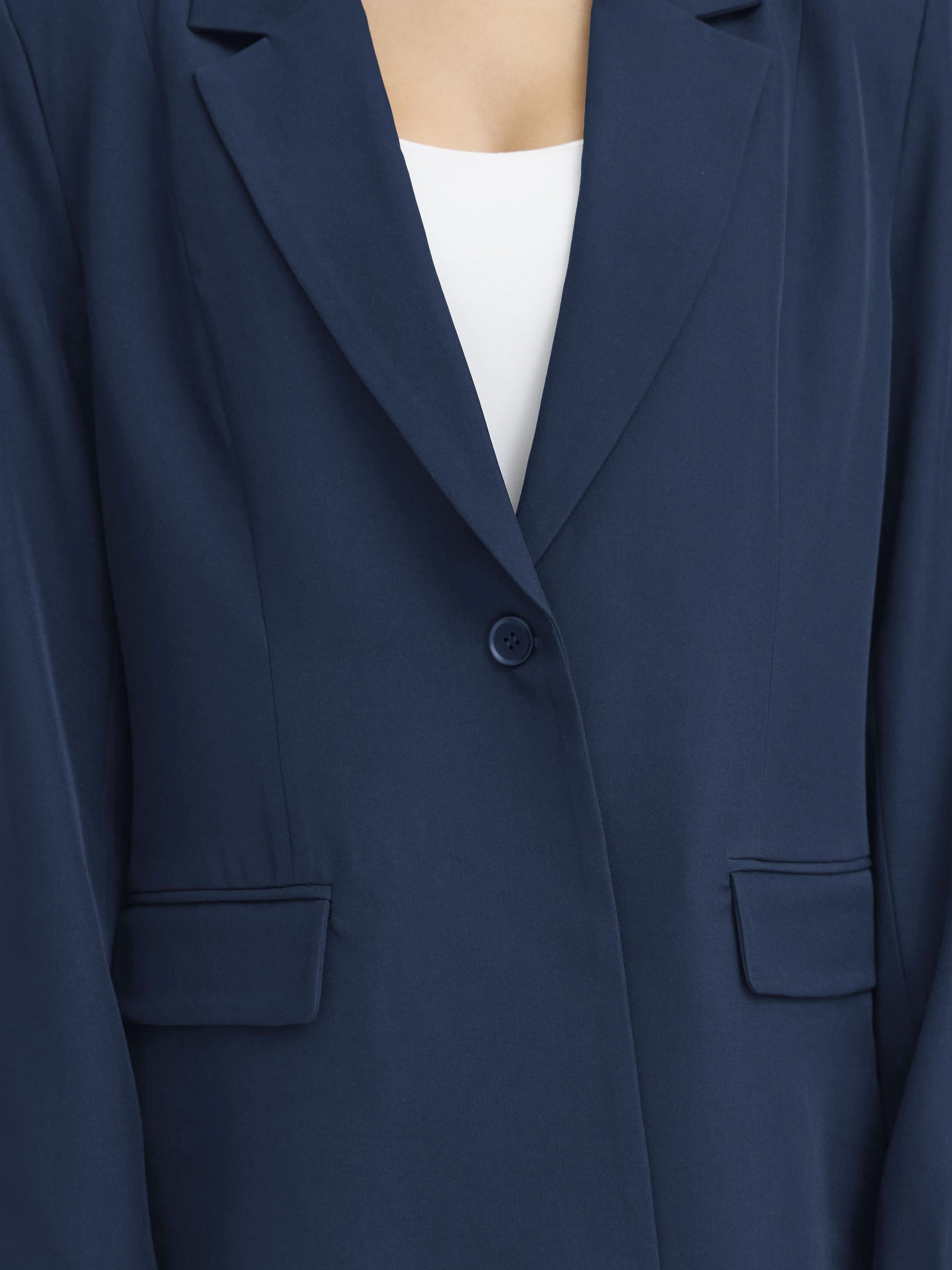 Close-up of a navy blue tailored jacket with notch lapels, button front, and flap pockets over a white top.