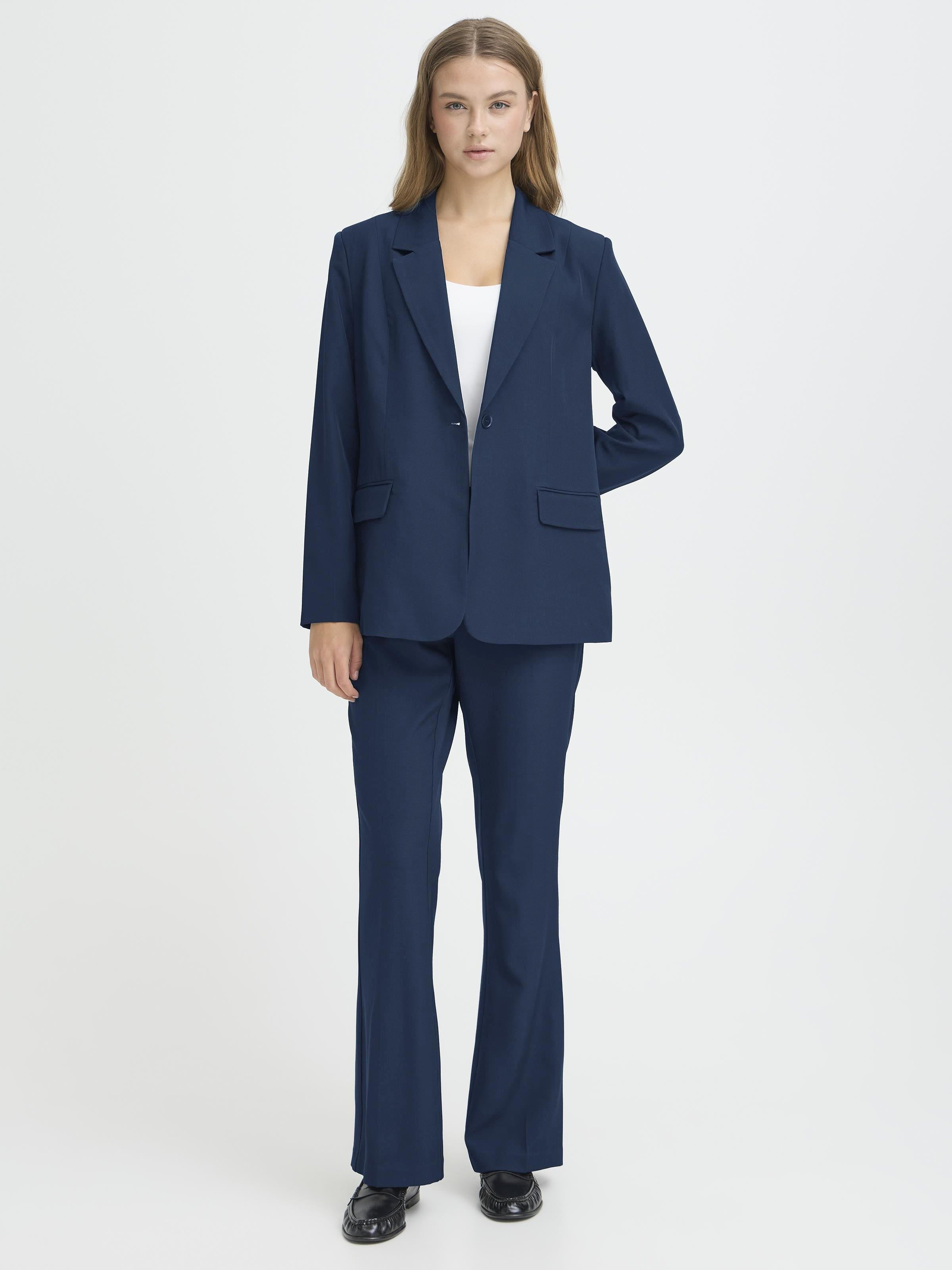 Navy blue tailored jacket and matching trousers paired with a white top and black shoes on a plain background.