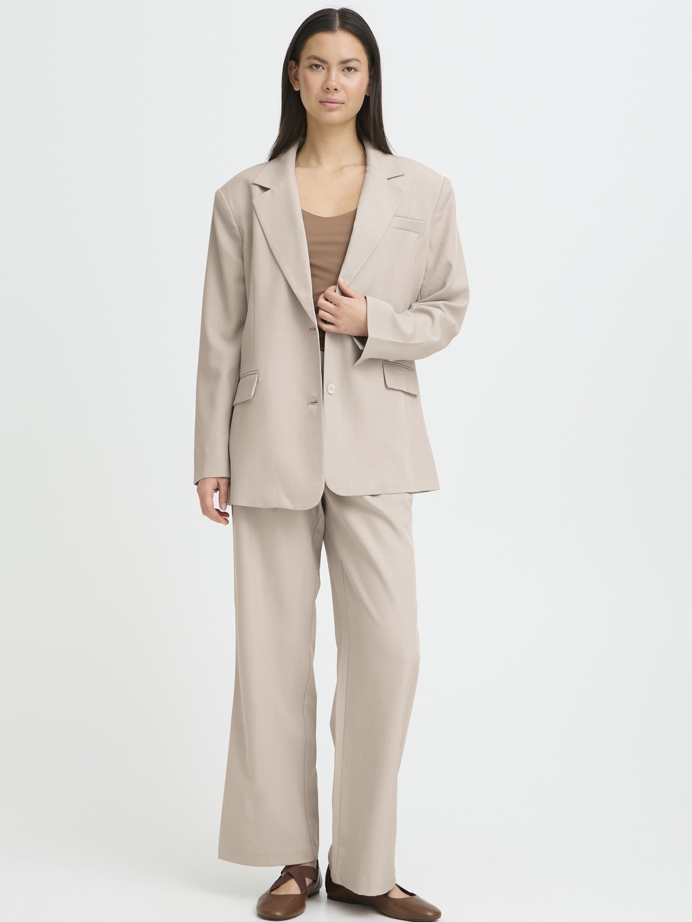 Beige oversized blazer and matching wide-leg trousers paired with a brown top and brown flats on a white background.