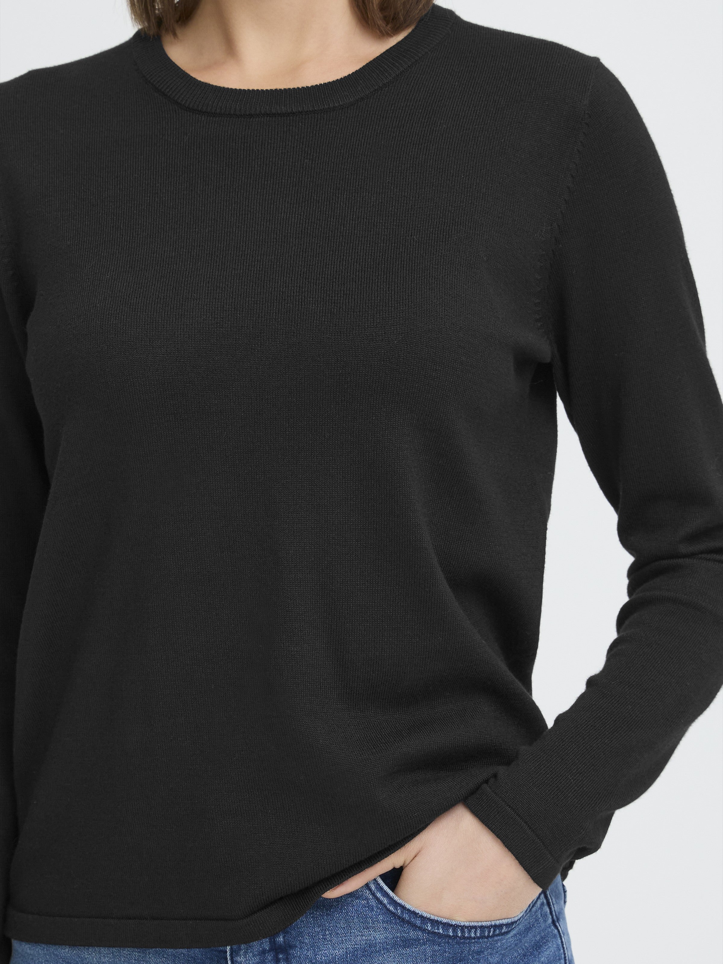 Black long-sleeve knit sweater paired with blue denim jeans, cropped at the torso and arm detail.