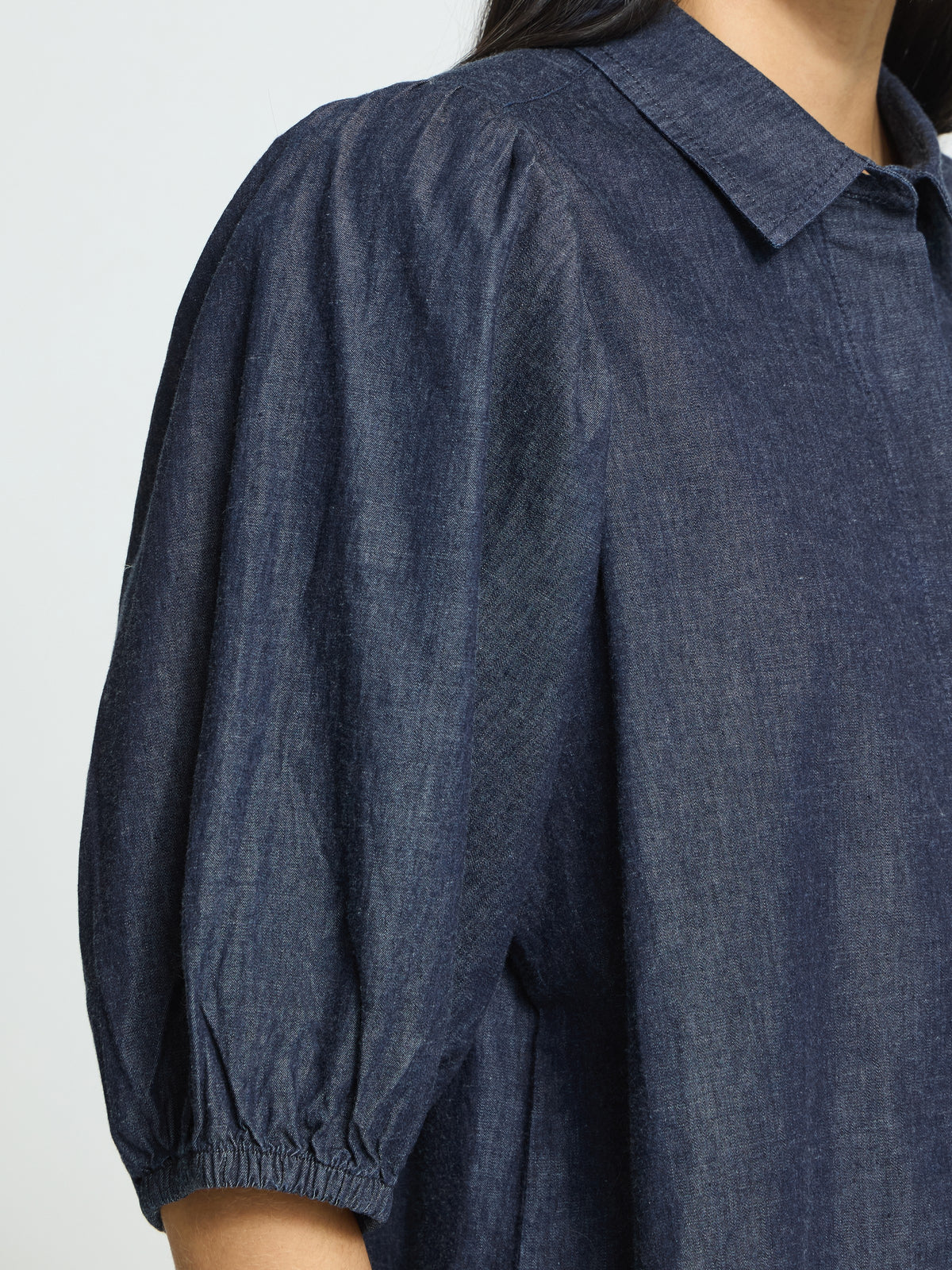 Close-up of dark denim top with puffed sleeves and a collar detail