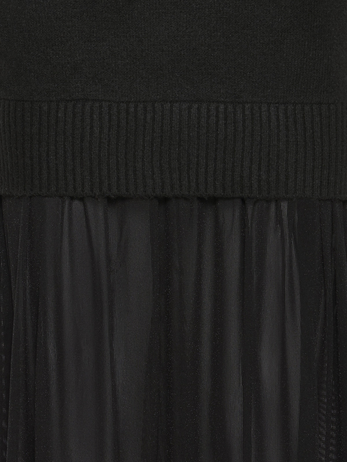 Close-up of black ribbed knit fabric above sheer pleated material in a layered garment design.