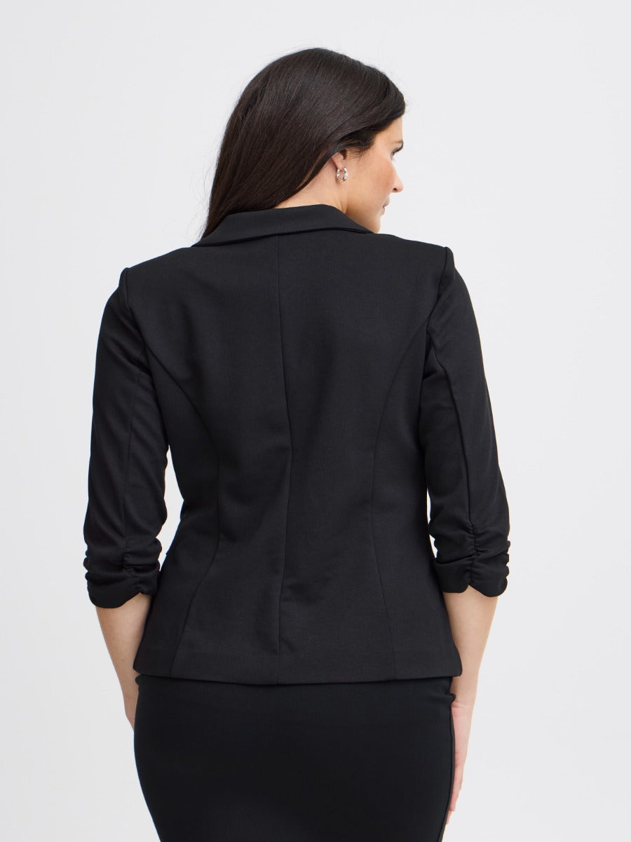 Back view of a black fitted jacket with ruched three-quarter length sleeves on a neutral background