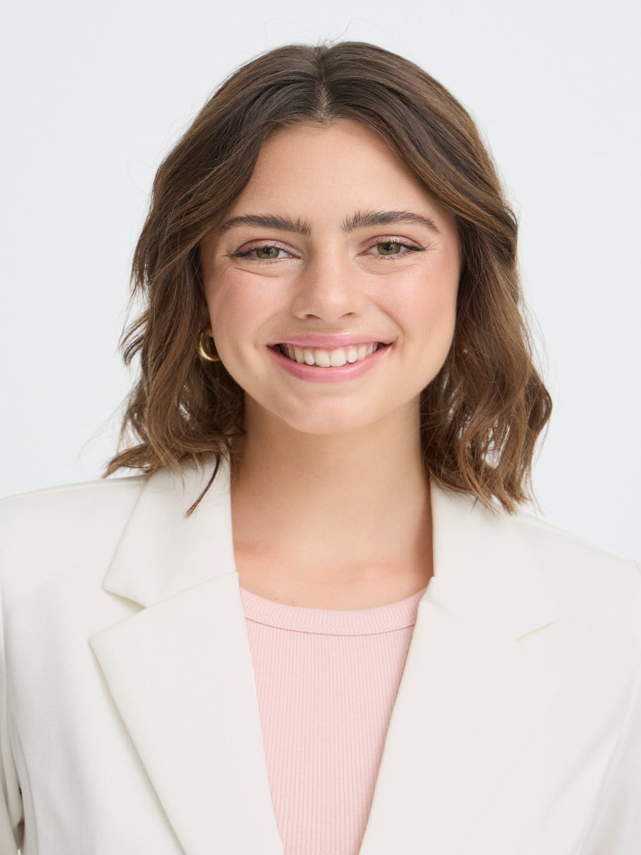 Close-up of a smiling face wearing an off-white Fransa Gathered Sleeve Stretch Blazer with gold hoop earrings