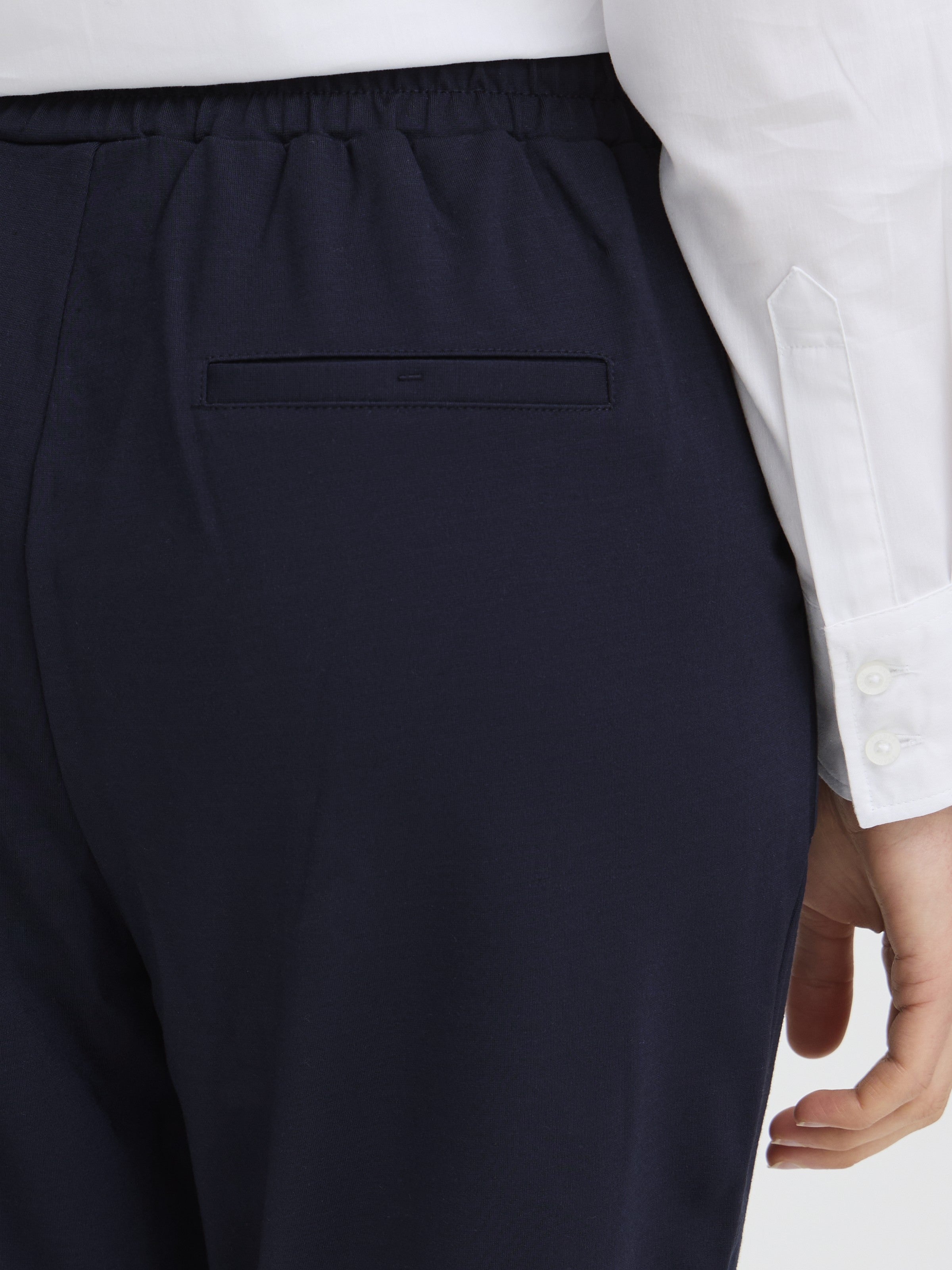 Close-up of navy Fransa Jenns Stretch Tailored Pants back pocket with elastic waistband detail and white shirt cuff visible