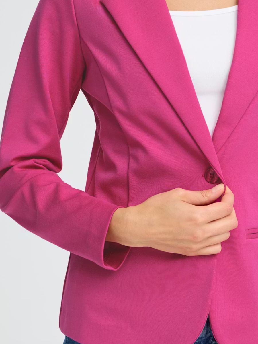 Close-up of a bright pink blazer jacket with a single button and white top underneath.